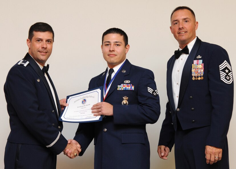 Senior Airman Israel Garcia, 2nd Security Forces Squadron, receives an Airman Leadership School graduation certificate from Col. Andrew Gebara, 2nd Bomb Wing commander, on Barksdale Air Force Base, La., Sept. 26, 2013. (U.S. Air Force photo)