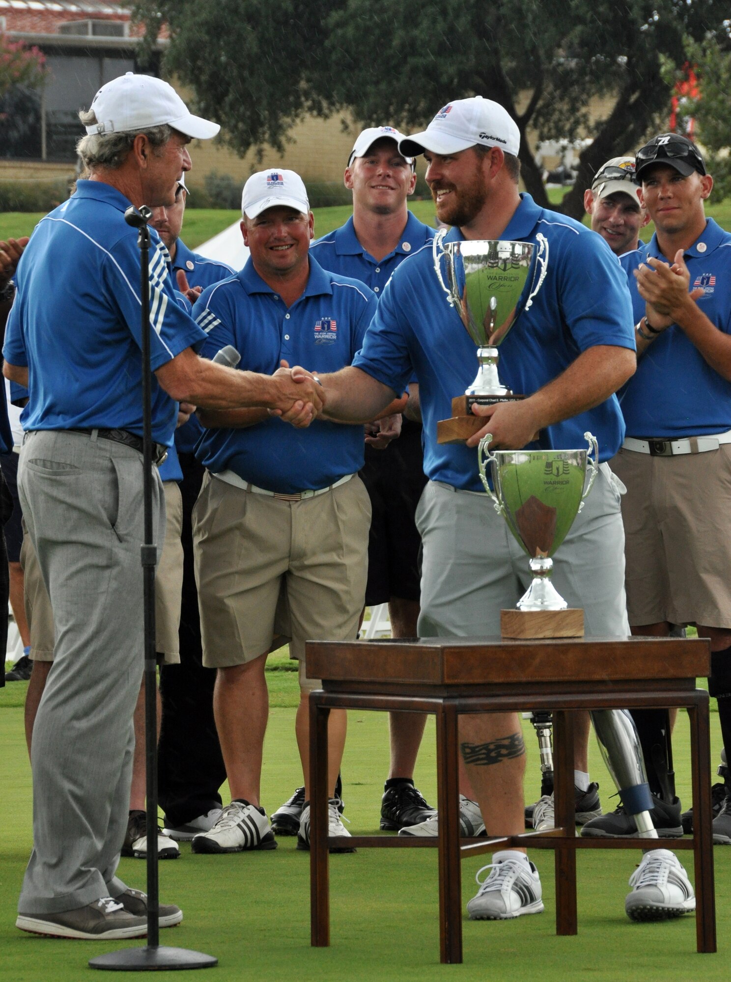 President Bush presents the Champion's Cup to Corporal Chad Pfeifer. Corporal Chad Pfeifer, U.S. Army, finished with the lowest overall score for the 3rd straight year. Eighteen wounded warriors from the Air Force, Army and Marines joined in a competitive two-day, 36-hole golf tournament that kicked off Sept. 26, 2013, to honor post-9/11 U.S. service members wounded in the global war on terror. (U.S. Air Force photo/MSgt Julie Briden-Garcia)