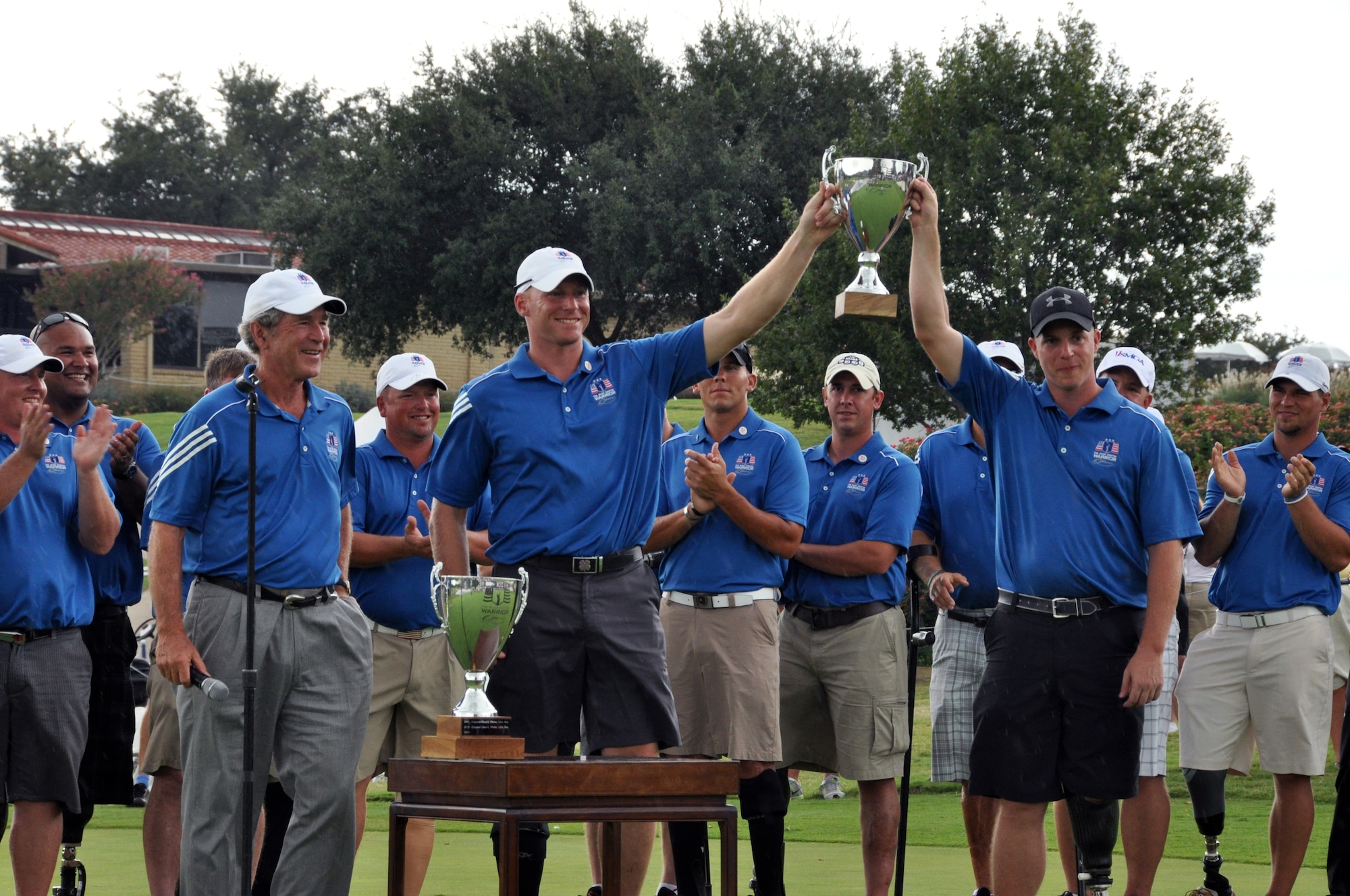 President Bush presents the Warrior Cup to Staff Sargeant Benjamin Dellinger and Captain Matthew Anderson at the 2013 Warrior Open. Staff Sargeant Dellinger and Captain Anderson win the first ever Warrior Cup by tying for the lowest net score. Eighteen wounded warriors from the Air Force, Army and Marines joined in a competitive two-day, 36-hole golf tournament that kicked off Sept. 26, 2013, to honor post-9/11 U.S. service members wounded in the global war on terror. (U.S. Air Force photo/MSgt Julie Briden-Garcia)