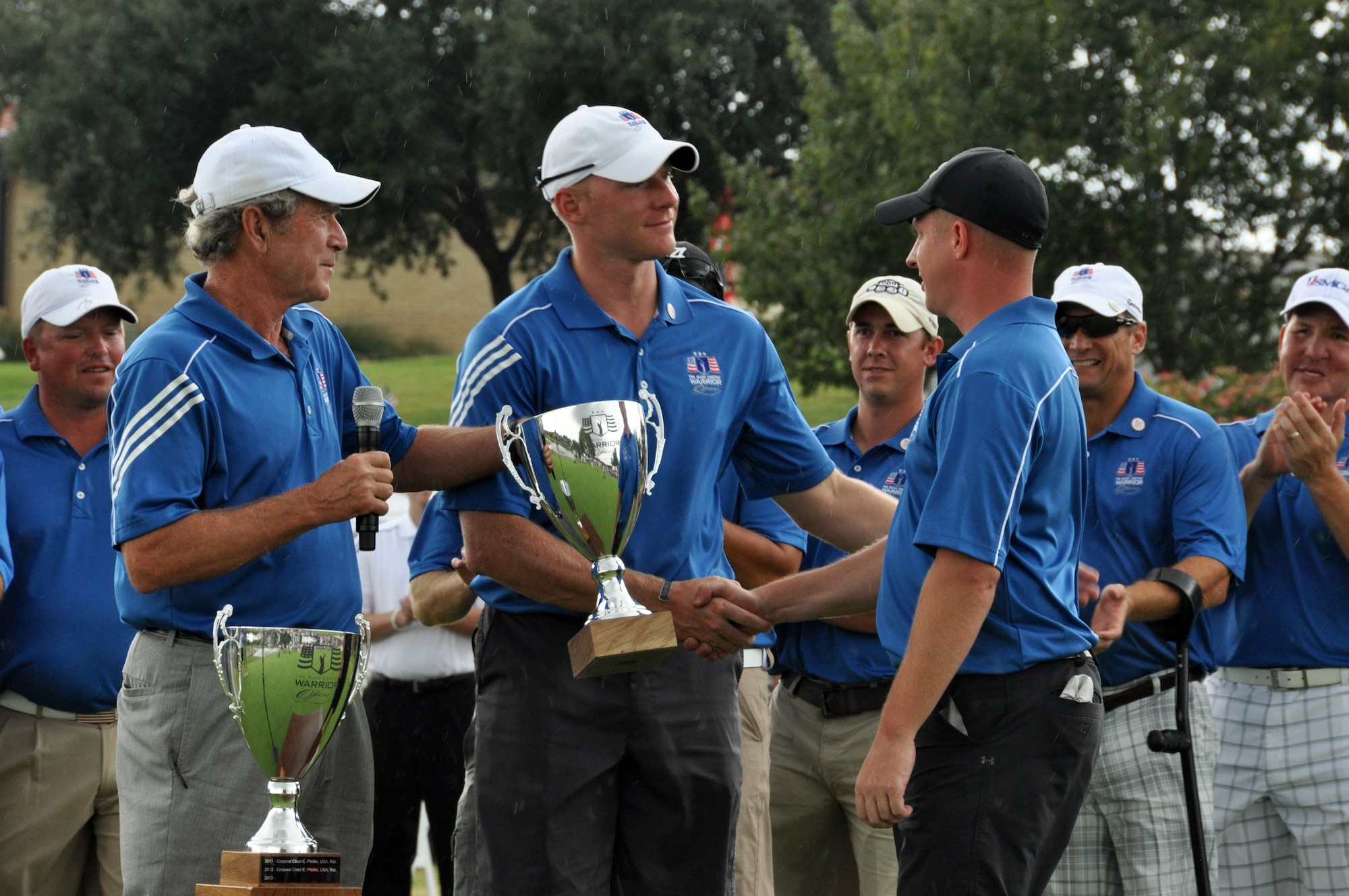 President Bush presents the Warrior Cup to U.S. Army Staff Sargeant Benjamin Dellinger and U.S. Army Captain Matthew Anderson at the 2013 Warrior Open. Staff Sargeant Dellinger and Captain Anderson win the first ever Warrior Cup by tying for the lowest net score. Eighteen wounded warriors from the Air Force, Army and Marines joined in a competitive two-day, 36-hole golf tournament that kicked off Sept. 26, 2013, to honor post-9/11 U.S. service members wounded in the global war on terror. (U.S. Air Force photo/MSgt Julie Briden-Garcia)