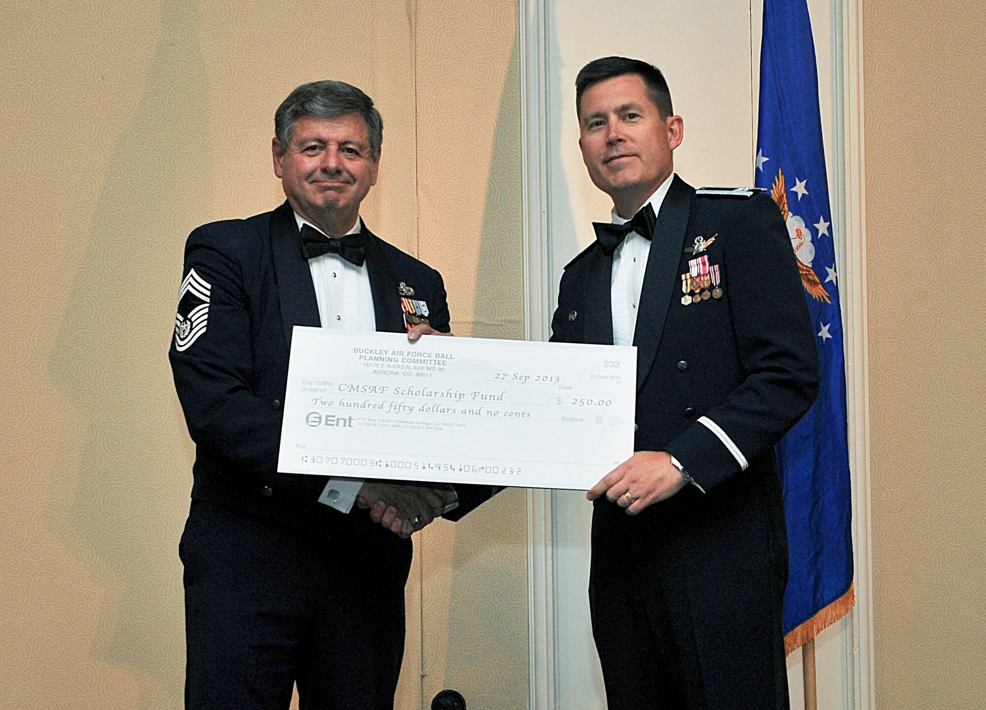 Col. Dan Wright, 460th Space Wing commander, right, hands a donation to Chief Master Sgt. of the Air Force David J. Campanale during the Air Force Ball Sept. 27, 2013, at the Renaissance Hotel in Denver. The donation was for the Chief Master Sergeant of the Air Force Scholarship Fund, a college scholarship given to children of enlisted active-duty and retired Airmen. This year’s celebration marked the 66th Air Force birthday and paid respects to 1st Lt. John Harold "Buck" Buckley the base’s namesake, who was killed during World War I 95 years ago. (U.S. Air Force photo by Senior Airman Phillip Houk/Released)