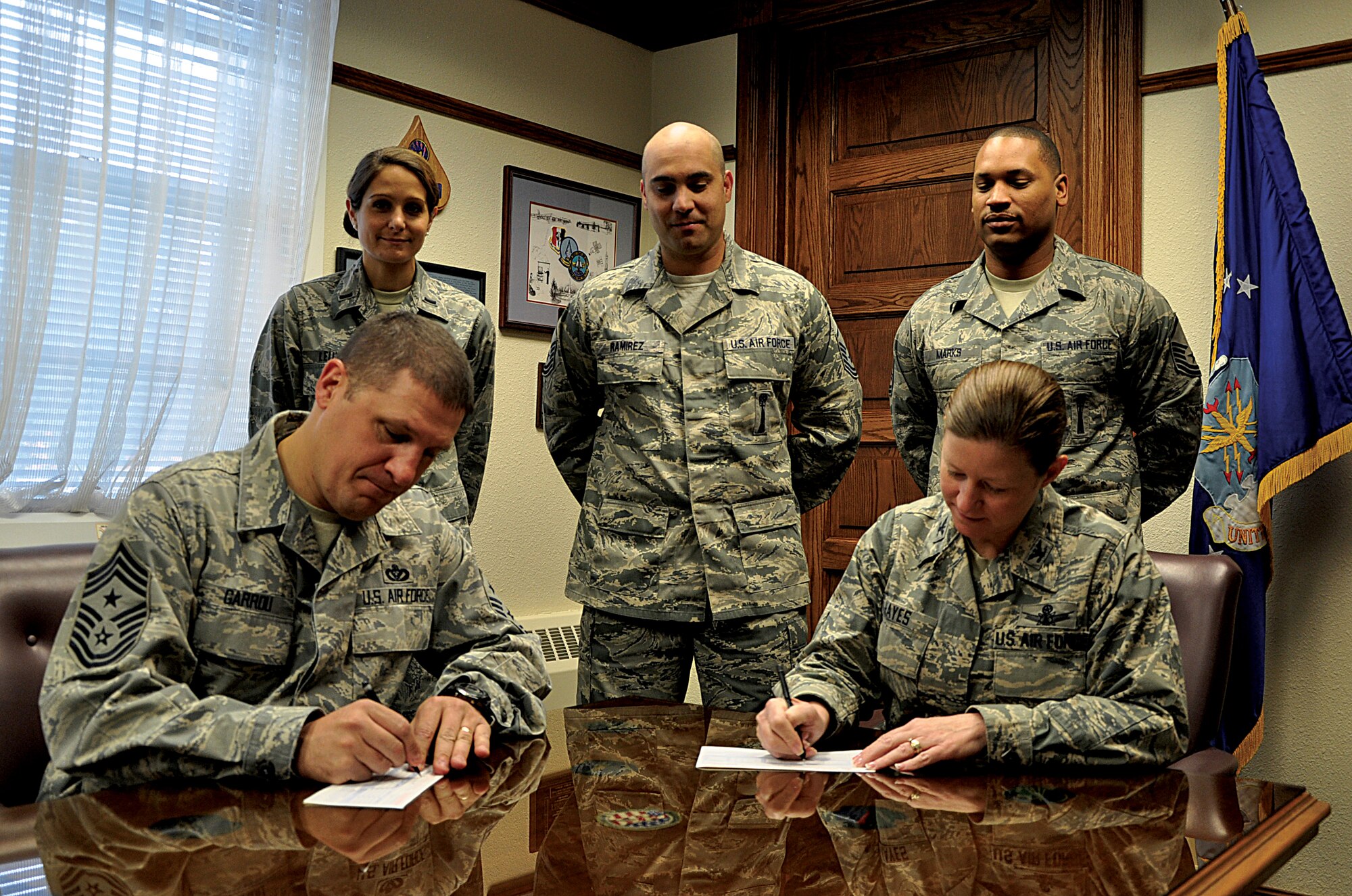 Col. Tracey Hayes, 90th Missile Wing commander, seated right; and Chief Master Sgt. Mike Garrou, 90th MW command chief, seated left; sign their Combined Federal Campaign donation slips in the commander’s office here Sept. 30, 2013, as CFC leads look on. This year’s campaign runs from Oct. 7 through Nov. 15, with a financial goal for the wing of $115,000. To donate, contact your unit’s CFC representative. (U.S. Air Force photo by Senior Airman Mike Tryon)