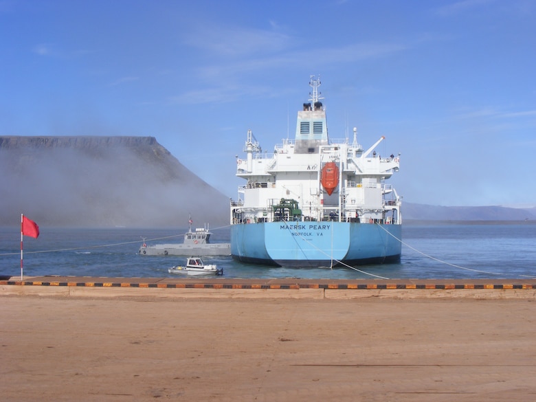 THULE AIR BASE, Greenland – The “Rising Star” tugboat pushes the Maersk Peary into a Mediterranean Moored position, used for shallow ports, during a fuel resupply mission. The tugboat also pulls the fuel lines from the ship to the pier to connect to a pipeline. (U.S. Air Force photo)