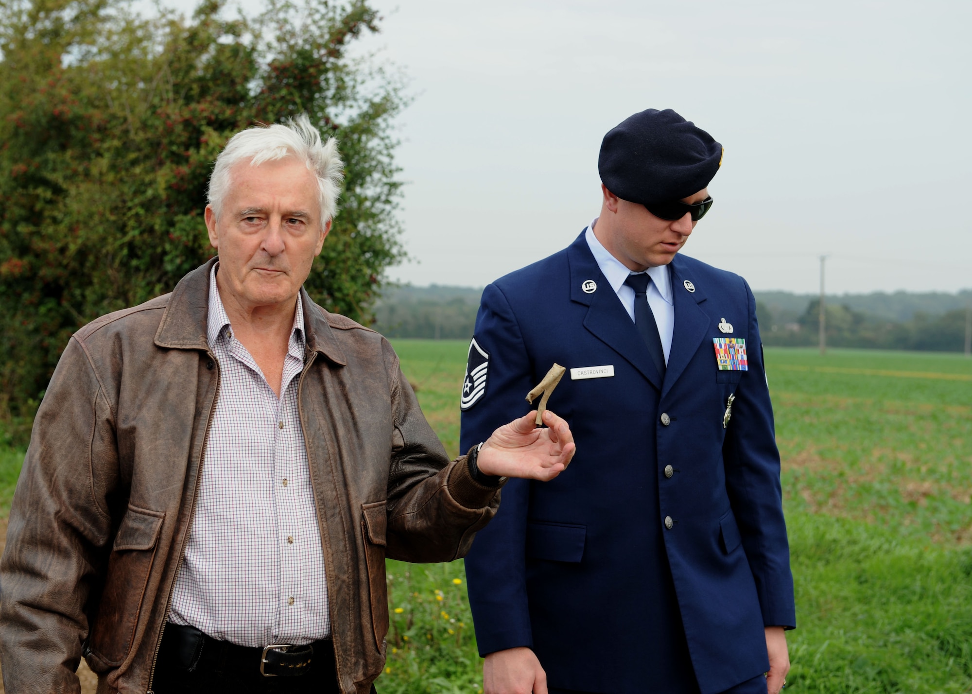 Fred Dunn, left, a chartered engineer who excavated the Dorsal Queen, a B-17 Flying Fortress, crash site in 1978, holds up a piece of tubing Sept. 28, 2013, found by U.S. Air Force Master Sgt. Scott Castrovinci, 100th Security Forces Squadron Installation Security Section NCO in charge, at the crash site. Though the site was excavated in 1978, pieces of the B-17 can still be found in the field where it crashed. Dunn believed the tubing could be a piece of the aircraft. (U.S. Air Force photo by Airman 1st Class Preston Webb/Released)