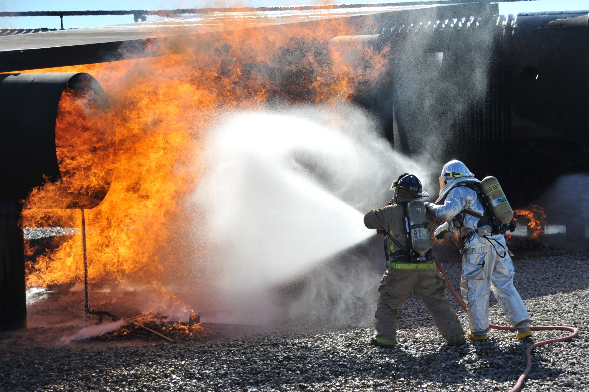 Members of the 377th Civil Engineer Squadron's firefighting unit practice skills on a burning aircraft during a training exercise Sept. 20. Personnel assigned to the fire department must achieve at least two aircraft live-fire trainings each year. (Photo by Ken Moore)