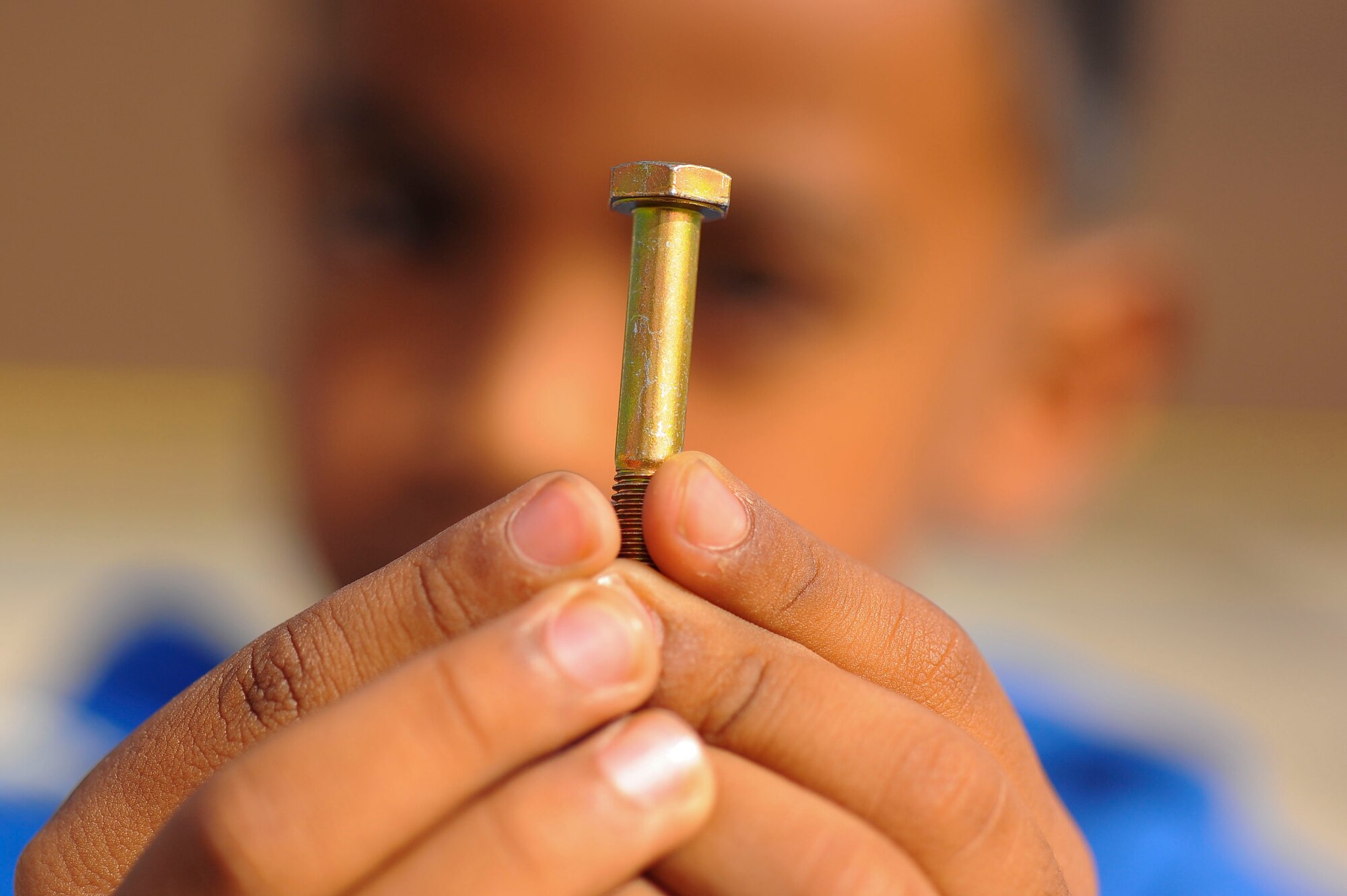 SPANGDAHLEM AIR BASE, Germany--A School-Age Program child holds a golden bolt on the flightline Sept. 27, 2013. The children who found the bolts received a prize as part of a foreign object debris tour. (U.S. Air Force photo by Senior Airman Rusty Frank/Released)