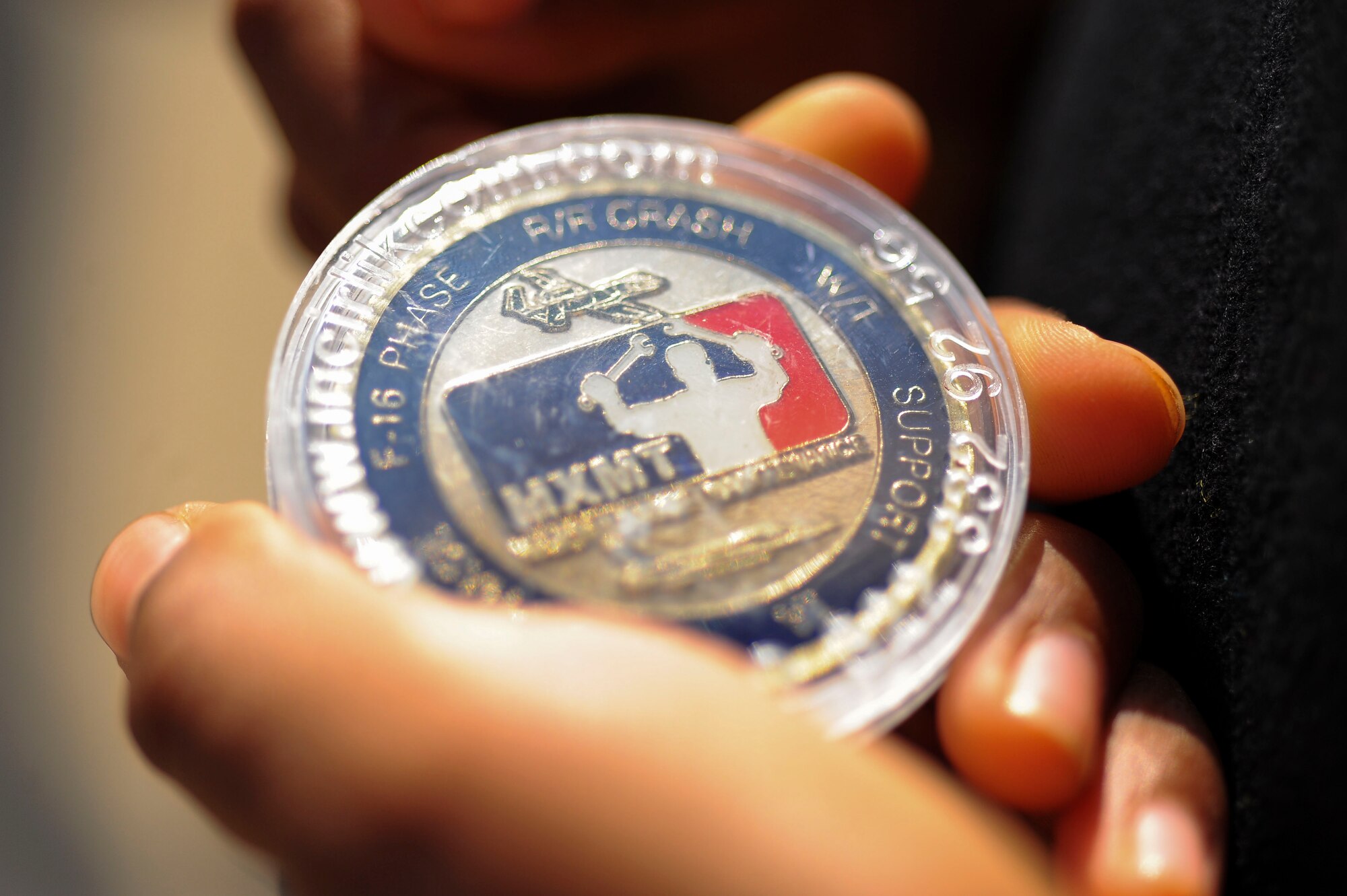 SPANGDAHLEM AIR BASAE, Germany--A School-Age Program child holds an Air Force Maintenance coin on the flightline Sept. 27, 2013. The child received the coin as a prize for finding a golden bolt during a foreign object debris tour. (U.S. Air Force photo by Senior Airman Rusty Frank/Released)