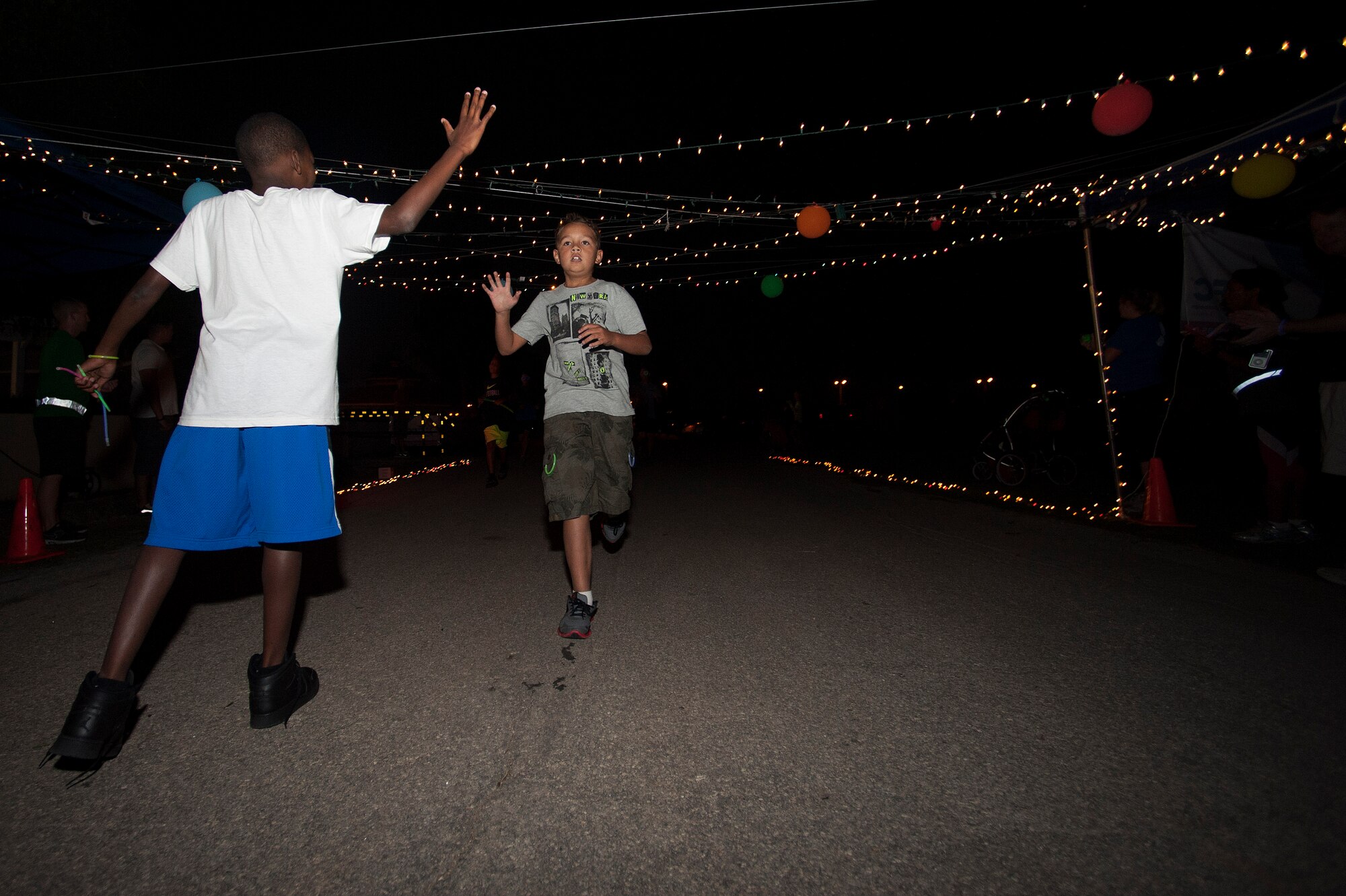 A child gives a high five as his friend finishes the Combine Federal Campaign Overseas glow run Sept. 30, 2013, at Incirlik Air Base, Turkey. The CFC-O raised more than $13.6 million in 2012 from the five unified combatant commands, demonstrating the generosity of overseas Department of Defense uniformed and civilian personnel. (U.S. Air Force photo by Airman 1st Class Nicole Sikorski/Released) 

