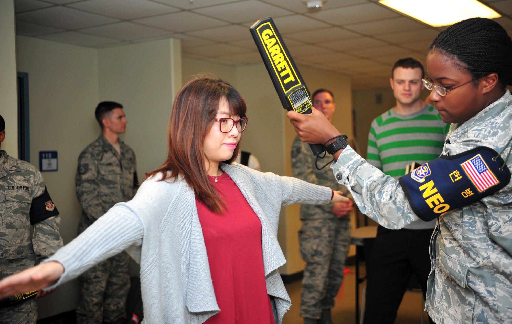 Senior Airman Elena Storr, 51st Munitions Squadron munitions systems journeyman, screens a noncombatant evacuation operations exercise participant with a metal-detecting wand at Osan Air Base, Republic of Korea, Sept. 27, 2013. In the event of an emergency, an estimated 10,000 to 20,000 noncombatants would follow the same steps as a NEO exercise participant to leave the peninsula. (U.S. Air Force photo/Airman 1st Class Ashley J. Thum)