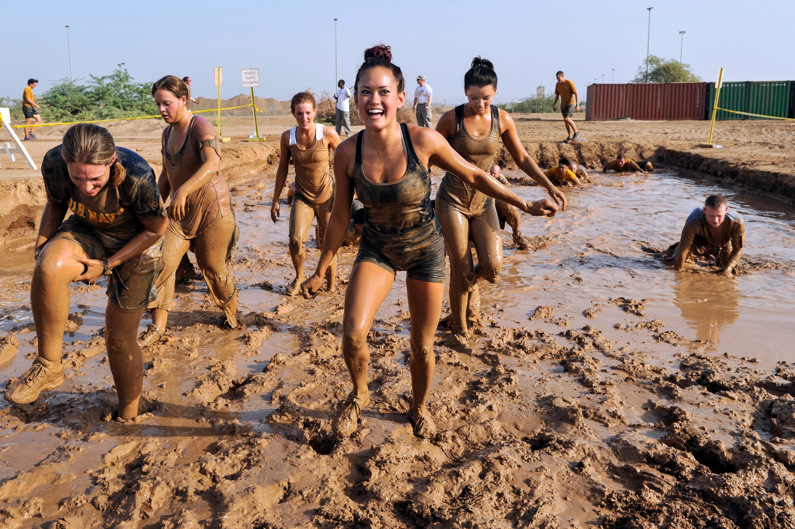 U.S. service members emerge from a mud pit during a 5K mud run on Camp