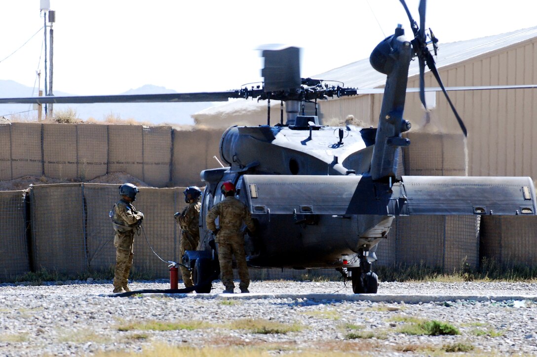 U.S. Army Spcs. Scott Pezzuto, left, and Garrett Pillow, center, wait as a petroleum supply specialist refuels their UH-60M Black Hawk helicopter at the forward arming and refueling point on Forward Operating Base Goode, Afghanistan, Sept. 25, 2013. Pezzuto and Pillow, crew chiefs, are assigned to Company C, 2nd Battalion, 10th Combat Aviation Brigade, Task Force Falcon.