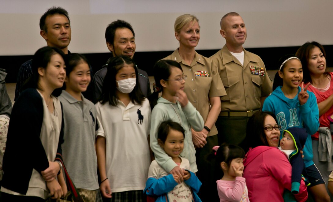 Master Labor Contract employees and their families stand with Col. Katherine J. Estes and Sgt. Maj. Jerry L. Bates II at the Camp Foster Theater March 28 during MLC Appreciation Day. “Everywhere I go, every office on my camp, every building, there are MLC employees,” said Estes. “I can’t say enough of how much we appreciate what you do and how much we appreciate your families for supporting you. You all are absolutely wonderful.” Estes is the camp commander of Camps Foster and Lester, and commanding officer of Headquarters and Service Battalion, Marine Corps Base Camp Smedley D. Butler, Marine Corps Installations Pacific. Bates is the sergeant major of the battalion. (U.S. Marine Corps photo by 