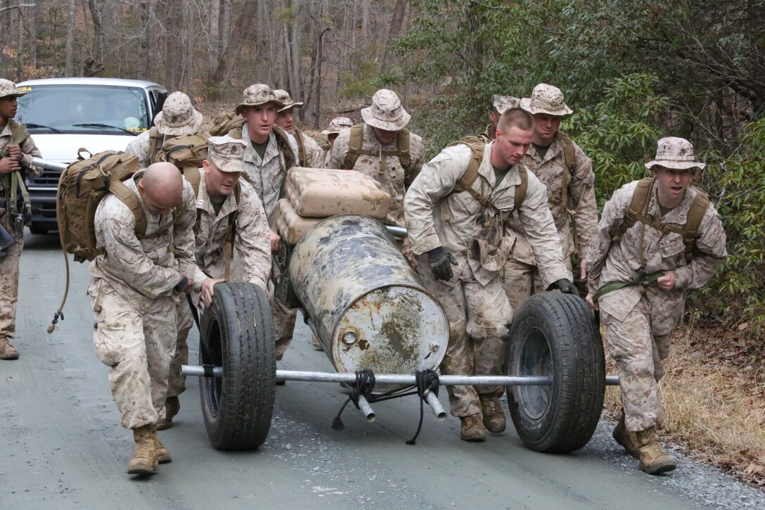 Permanent personnel Marines from the Officer Candidates School work as a team to transport items including a 400-pound, 55-gallon drum, ammo cans and water jugs with only minimal gear aboard Marine Corps Base Quantico on March 28, 2014. The challenge was part of an eight-station training event that Headquarters and Service Co. Marines participated in.