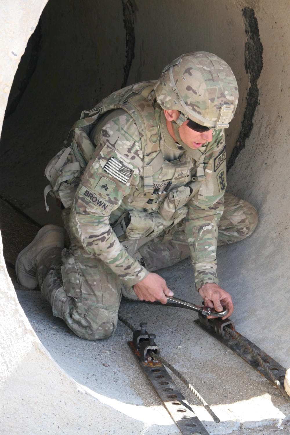 U.S. Army soldier, Sgt. Nathan Brown, route clearance, 65th Engineer Battalion, secures the tension force cables for the culvert denial systems the Battalion is installing along Highway 1 in Helmand province, Afghanistan, March 24. The systems are designed to prevent the emplacement of improvised explosive devices in small tunnels along the main highway in Helmand and ensure the safety of the Afghan people traveling along the road.