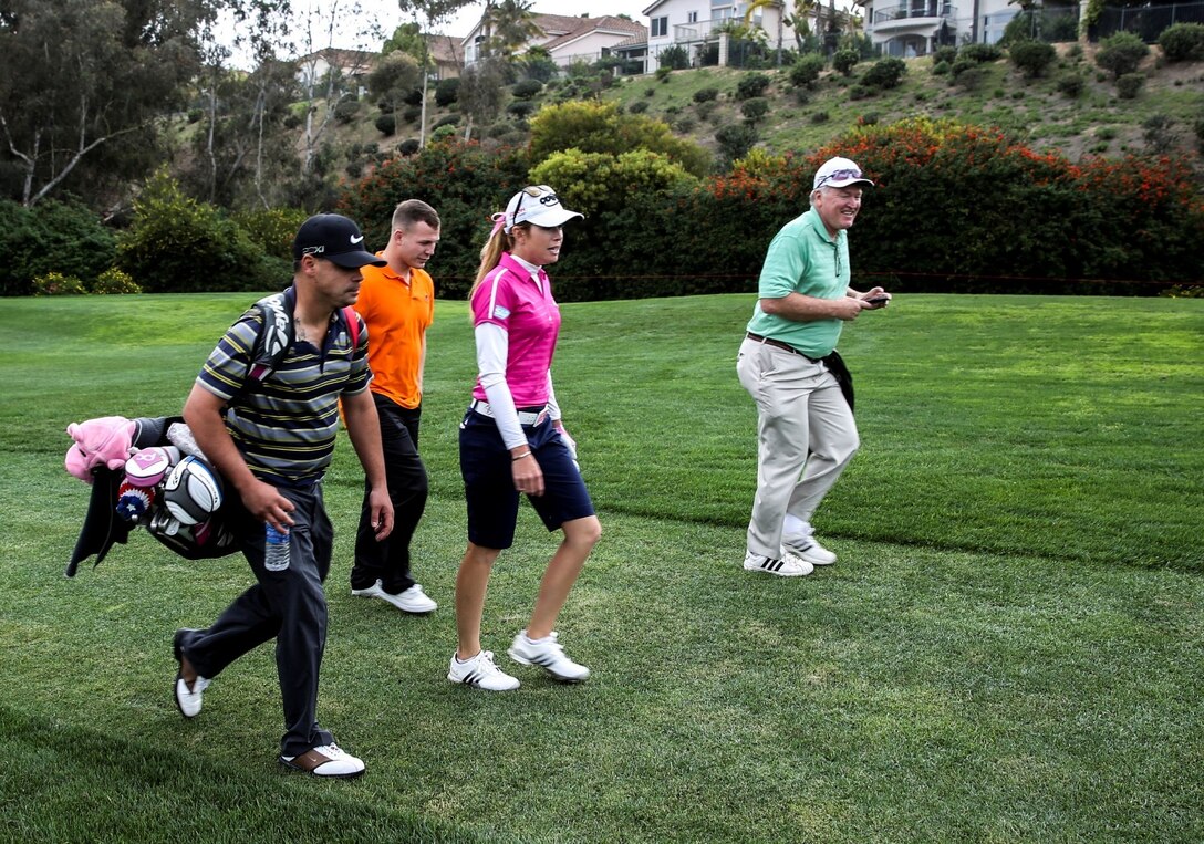 Staff Sgt. Matthew Castel, left, radio frequency manager, 15th Marine Expeditionary Unit, caddies for Paula Creamer, center, Ladies Professional Golf Association player, during a practice round at the Aviara Golf Club in Carlsbad, Calif., March 25, 2014. Creamer was raised in a military family and is dedicated to giving back to service members. (U.S. Marine Corps photo by Cpl. Emmanuel Ramos/Released)