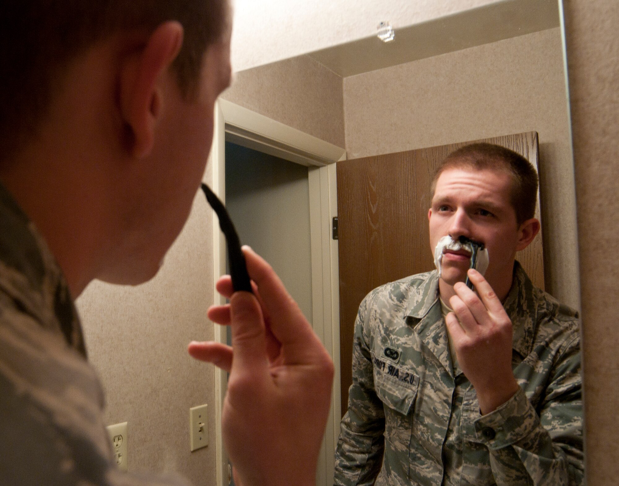Airman 1st Class Jason Wiese, 90th Missile Wing Public Affairs photojournalist, gazes forlornly into a mirror at his home as he shaves the mustache he had grown to love over the course of the month as Mustache March drew to an end. (Photo illustration by Nicole Wiese)