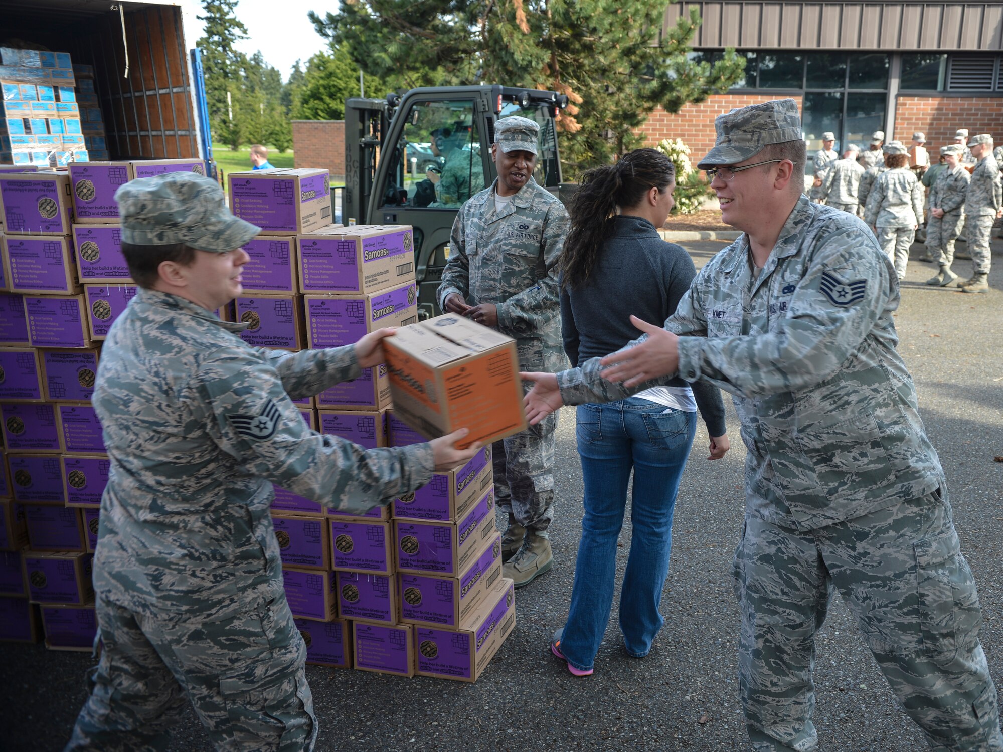 Staff Sgt. Shane Kmet, 62nd Maintenance Squadron, is handed a box of Girl Scout Cookies as he helps other McChord Airmen unload trucks for the USO, Apr. 1, 2014 at Joint Base Lewis-McChord, Wash. Six trucks full of donated cookies arrived on station and were quickly offloaded by the volunteer Airmen. (U.S. Air Force photo by Staff Sgt. Russ Jackson)