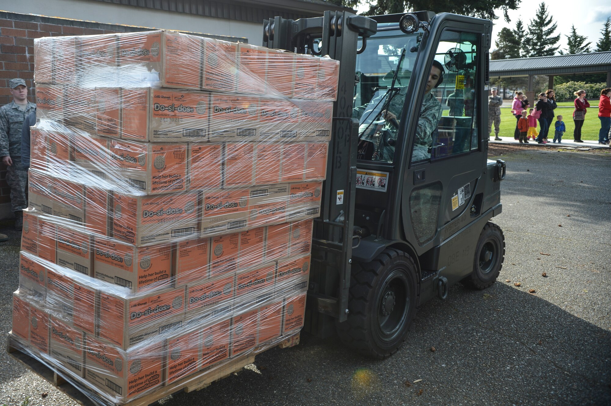 Senior Airman Joseph Sosa, 62nd Aerial Port Squadron Passenger Services agent, forklifts a pallet of Girl Scout Cookies to a line of Airmen waiting to break it down and distribute the cookies, Apr. 1, 2014 at Joint Base Lewis-McChord, Wash. The USO received help from McChord Airmen after receiving more than 100,000 boxes of donated cookies. (U.S. Air Force photo by Staff Sgt. Russ Jackson)