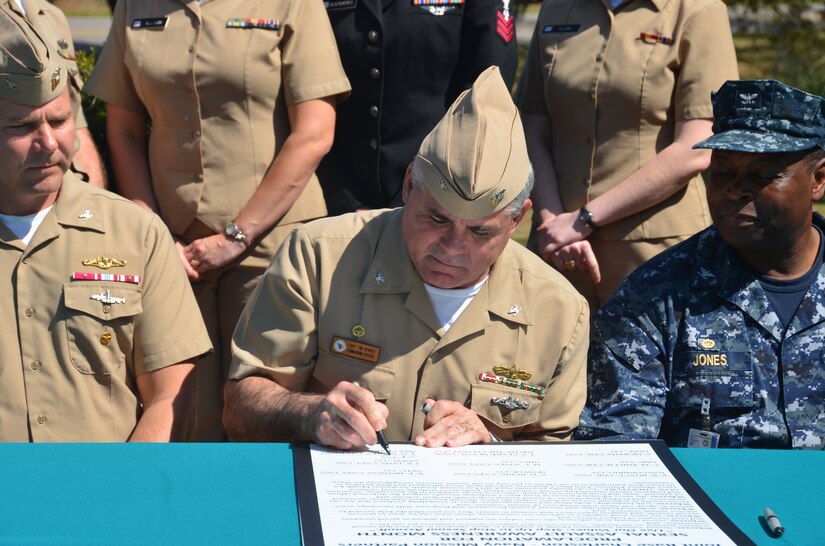 Capt. Timothy Sparks, Naval Support Activity Commanding Officer signs the Sexual Assault Awareness Proclamation April 1, 2014, while Capt. Jon Fahs, Naval Nuclear Power Training Command commanding officer (left), and Capt. Marvin Jones, Naval Health Clinic Charleston commanding officer, look on. The proclamation states that April is Sexual Assault Awareness Month, and encourages Sailors to “Live our values: step up to stop sexual assault.” (U.S. Air Force photo/Eric Sesit)