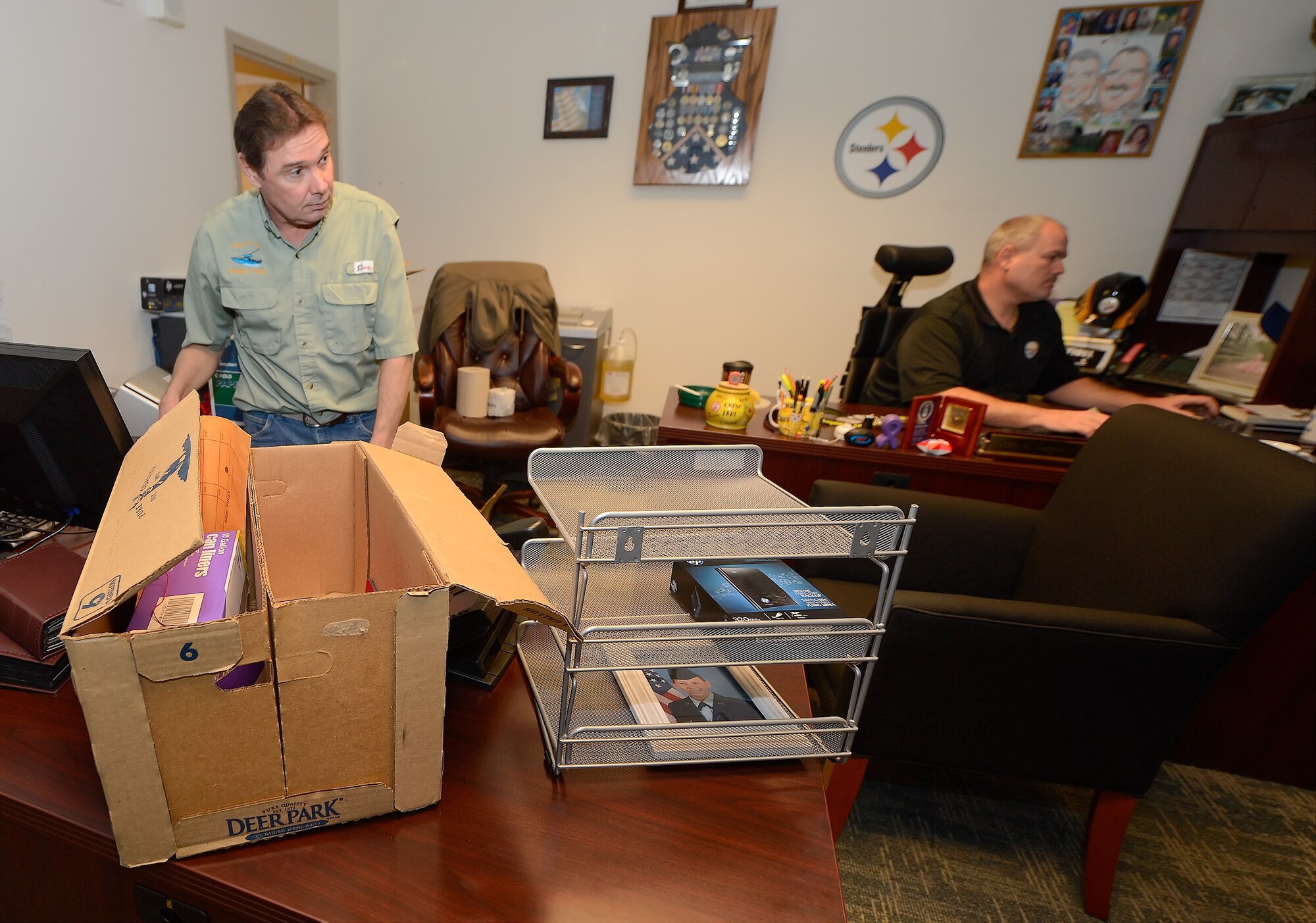 John McCann, standing, and John Van der Ven, seated, Dover's Information Protection Office, are shown getting settled in to their new office space within the Security Forces Squadron on April 1, 2014, at Dover Air Force Base, Del. The Anti-Terrorism and Information Protection function has been realigned and consolidated within the 436th SFS. (U.S. Air Force photo/Greg L. Davis)