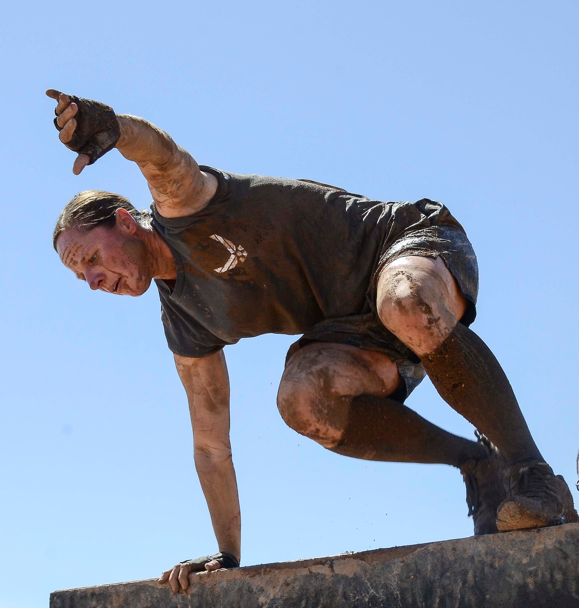 Capt. Yvonne Nollmann, 12th Air Force (Air Forces Southern) Section Commander, hurdles over a wall during the Hard Charge Televised Obstacle Mission at the Pima County Fairgrounds in Tucson, Ariz., on March 29. Climbing, crawling and sprinting were a few of the many ways the members form 12th AF maneuvered though the rigorous four-mile 37-obstacle course. (U.S. Air Force photo by Staff Sgt. Adam Grant/Released)
