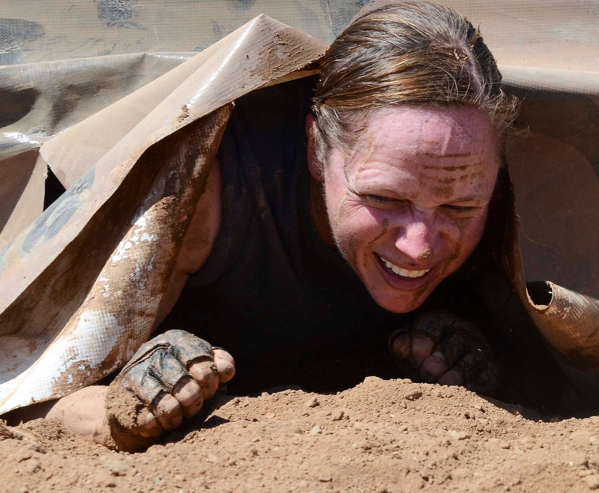 Capt. Yvonne Nollmann, 12th Air Force (Air Forces Southern) Section Commander, crawls from underneath a tarp during the Hard Charge Televised Obstacle Mission at the Pima County Fairgrounds in Tucson, Ariz., on March 29. Climbing, crawling and sprinting were a few of the many ways the members form 12th AF maneuvered though the rigorous four-mile 37-obstacle course. (U.S. Air Force photo by Staff Sgt. Adam Grant/Released)