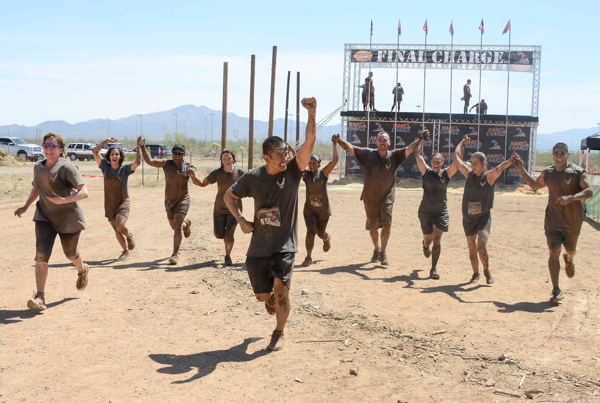 Members from 12th Air Force (Air Forces Southern) hold hands as the complete the Hard Charge Televised Obstacle Mission at the Pima County Fairgrounds in Tucson, Ariz., on March 29 as a team. The team of 11 members completed the four mile course with of obstacles designed to utilize a mix of strength, stamina, balance, and body awareness  that pushed participants to both mental and physical fatigue. (U.S. Air Force photo by Staff Sgt. Adam Grant/Released)
