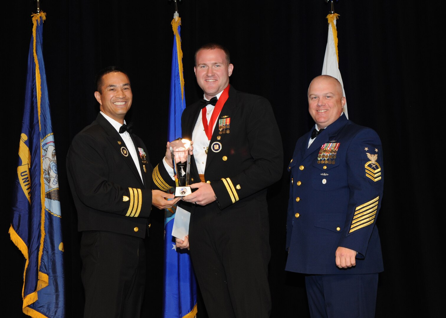 Representing the Coast Guard for award presentations during the Joint Base San Antonio Annual Awards Banquet March 29 are Commander Gene Anzano, left, and Master Chief Intelligence Specialist Alan Paul, right. Petty Officer 1st Class Joseph Gribbins, center, from the Coast Guard Recruiting Office San Antonio, received the NCO of the Year Award. (U.S. Air Force photo by Melissa Peterson)