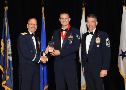 Representing the Air Force for award presentations during the Joint Base San Antonio Annual Awards Banquet March 29 are Brig. Gen. Bob Labrutta, left, and Chief Master Sgt. Alex Perry, right. Senior Airman Steven Koster, center, from the 37th Training Wing, received the Junior Enlisted Member of the Year Award. (U.S. Air Force photo by Melissa Peterson)