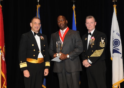 Representing the Navy for award presentations during the JBSA Annual Awards Banquet March 29 are Rear Adm. Bill Roberts, left, and Command Master Chief Petty Officer Christopher Angstead, right. Tony Cloud, center, from the Navy Technical Training Center, received the Civilian Supervisory Category II of the Year Award. (U.S. Air Force photo by Melissa Peterson)

