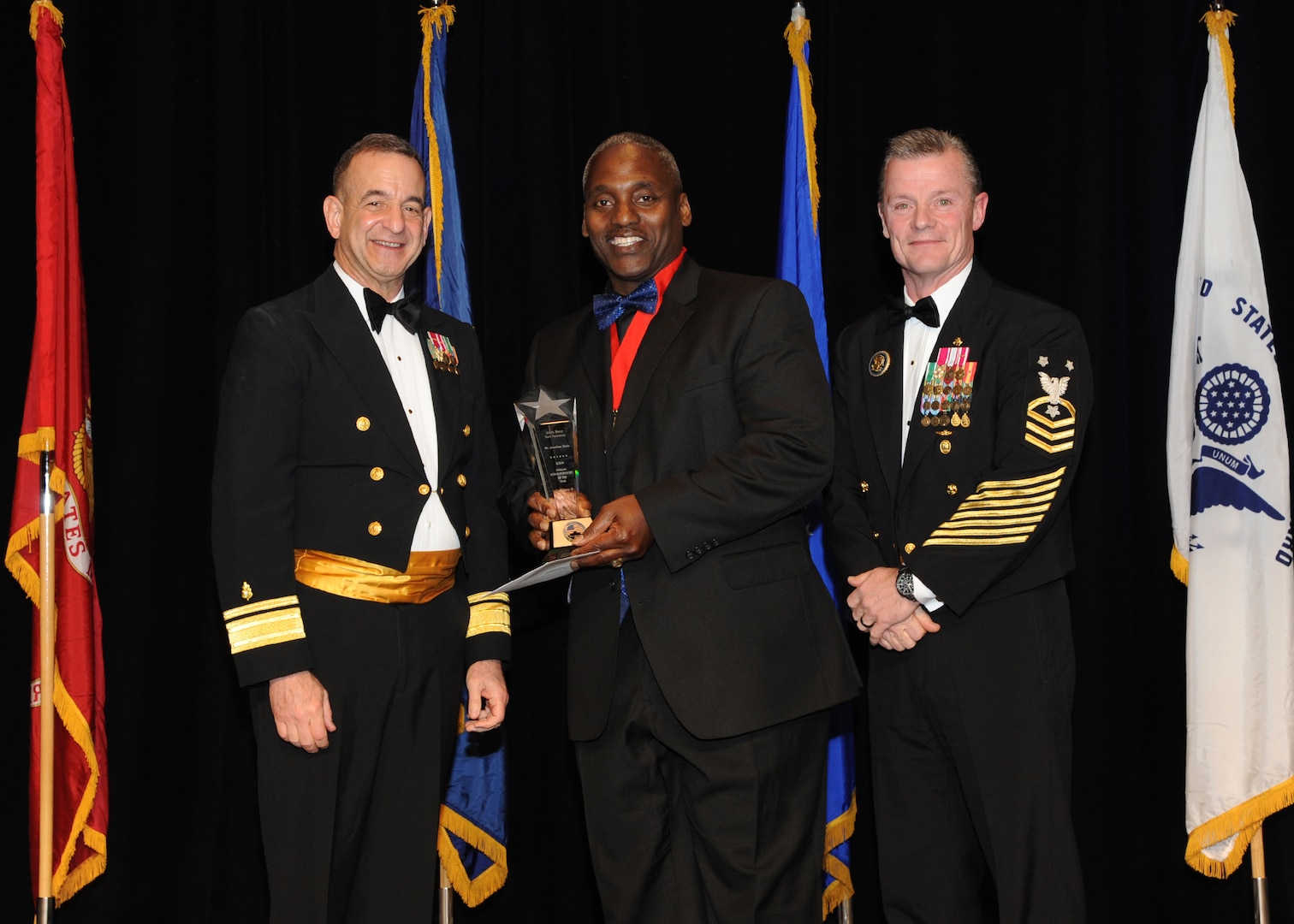 Representing the Navy for award presentations during the Joint Base San Antonio Annual Awards Banquet March 29 are Rear Adm. Bill Roberts, left, and Command Master Chief Petty Officer Christopher Angstead, right. Jonathan Davis, center, from the Navy Medicine Training Support Center, received the Civilian Non-Supervisory Category II of the Year Award.(U.S. Air Force photo by Melissa Peterson)