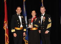 Representing the Navy for award presentations during the Joint Base San Antonio Annual Awards Banquet March 29 are Rear Adm. Bill Roberts, left, and Command Master Chief Petty Officer Christopher Angstead, right. Chief Petty Officer Emilia Guerrero, center, from the Center for Security Forces, received the Large Unit Category First Sergeant of the Year Award. (U.S. Air Force photo by Melissa Peterson)