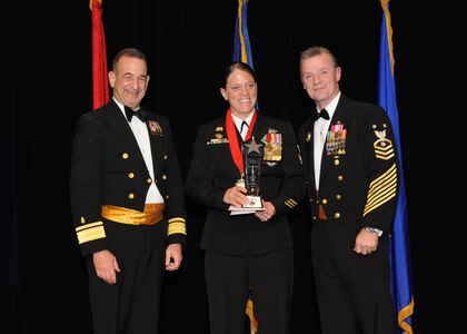 Representing the Navy for award presentations during the Joint Base San Antonio Annual Awards Banquet March 29 are Rear Adm. Bill Roberts, left, and Command Master Chief Petty Officer Christopher Angstead, right. Chief Hospital Corpsman Delilah Clymer, center, from the Navy Technical Training Center, received the Small Unit Category First Sergeant of the Year Award. (U.S. Air Force photo by Melissa Peterson)