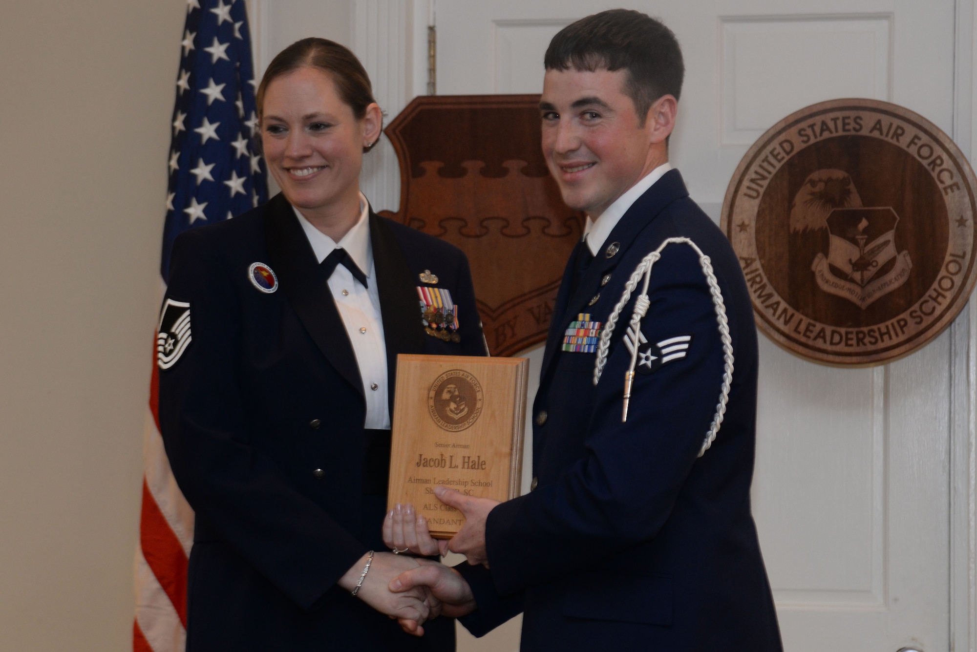 U.S. Air Force Senior Airman Jacob Hale, Detachment 4, 18th Weather Squadron, recieves the Commandants Award from Airman Leadership School class 14-3 from Master Sgt. Lindsey Wolf, Senior Master Sgt. David B. Reid Airman Leadership School commandant, Shaw Air Force Base, S.C., March 27, 2014. This award is presented to the student who most exemplifies professional military qualities as chosen by their peers, the primary instructors and the ALS commandant. (U.S. Air Force photo by Airman 1st Class Michael A. Cossaboom/Released)