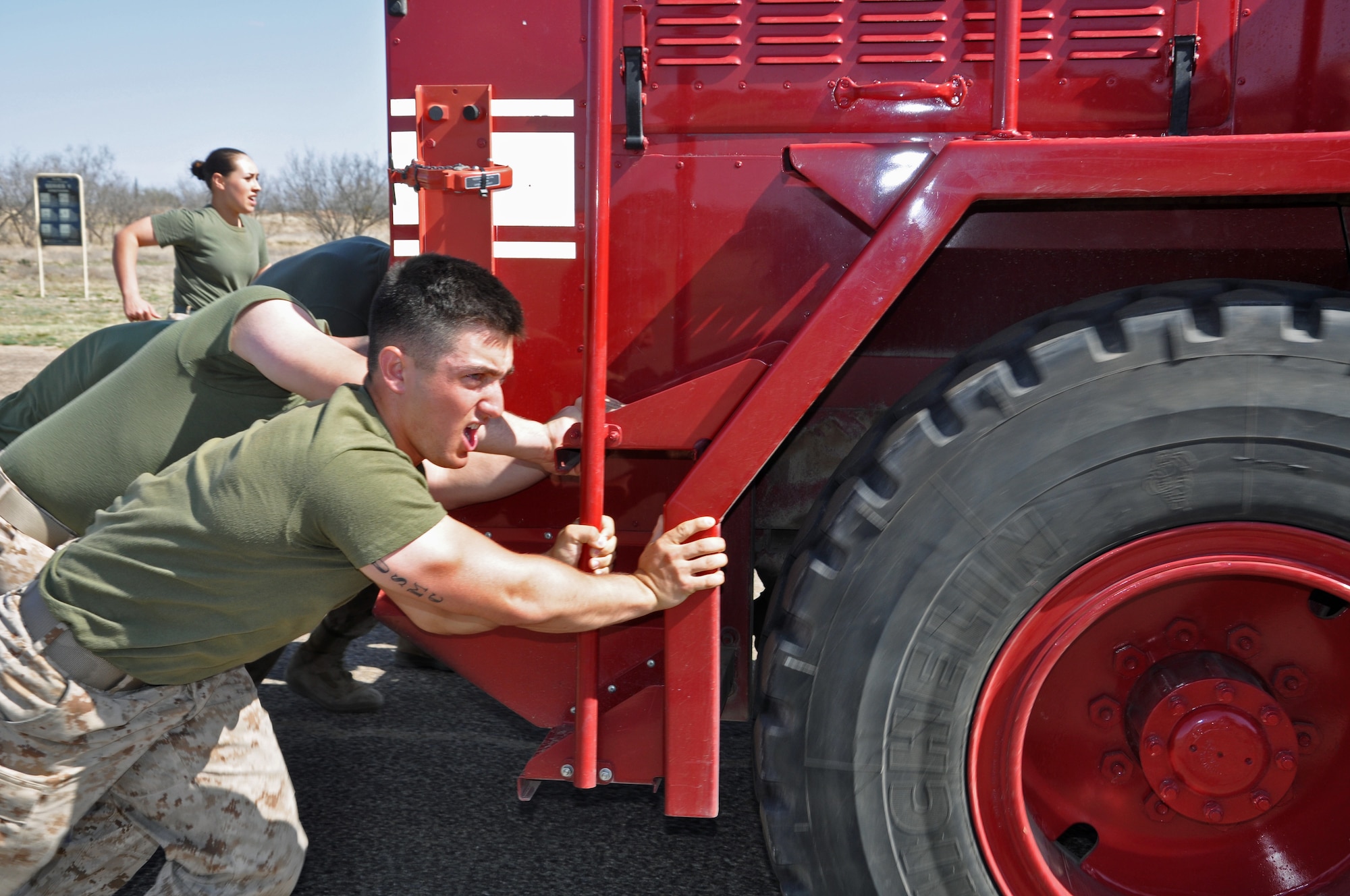 GOODFELLOW AIR FORCE BASE, Texas- Marine Corps Pfc. Steven Remedi, Marine Corps Detachment student, encourages his team as they push a fire truck during the Barracks Bash here March 28. In this particular event, five members from each team sprinted 50 yards to pick up and carry 10-gallon water jugs and then the rest of the team pushed a fire truck 50 yards across the finish line in the quickest time. (U.S. Air Force photo/ Airman 1st Class Erica Rodriguez)