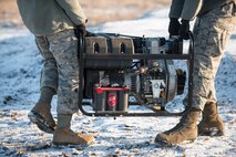 Airmen from the 5th Civil Engineer Squadron carry a generator to a Precision Approach Path Indicator during light checks at Minot Air Force Base, N.D., March 19, 2014. The PAPI acts as temporary runway lighting, two red lights indicate to a pilot that there aircraft is too low, two white lights indicate too high of an altitude. To achieve a safe landing the pilot must ensure that their aircraft is at the right height and angle to allow a red and a white light to be visible; this will ensure a safe touchdown. (U.S. Air Force photo/Senior Airman Stephanie Sauberan)