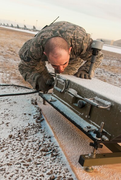 Staff Sgt. Wayde Waltjen, 5th Civil Engineer Squadron electrical systems supervisor clears snow from a Precision Approach Path Indicator at Minot Air Force Base, N.D., March 19, 2014. The taxiway on which the PAPI is installed will act as an emergency runway during flight line construction to occur later this year. (U.S. Air Force photo/Senior Airman Stephanie Sauberan)