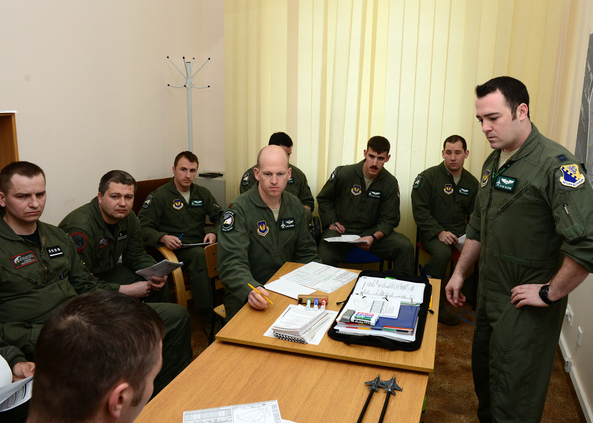 U.S. and Polish pilots listen to a pre-flight briefing, April 1, 2014, prior to their first training sortie together at Łask Air Base, Poland. Some of the training will focus on communication effectiveness and familiarization of techniques to strengthen interoperability with a key NATO ally since the 555th Fighter Squadron from Aviano Air Base, Italy, and the Polish air force’s 10th Tactical Squadron from Łask employ the F-16 Fighting Falcon fighter aircraft. (U.S. Air Force photo/Airman 1st Class Ryan Conroy/Released) 