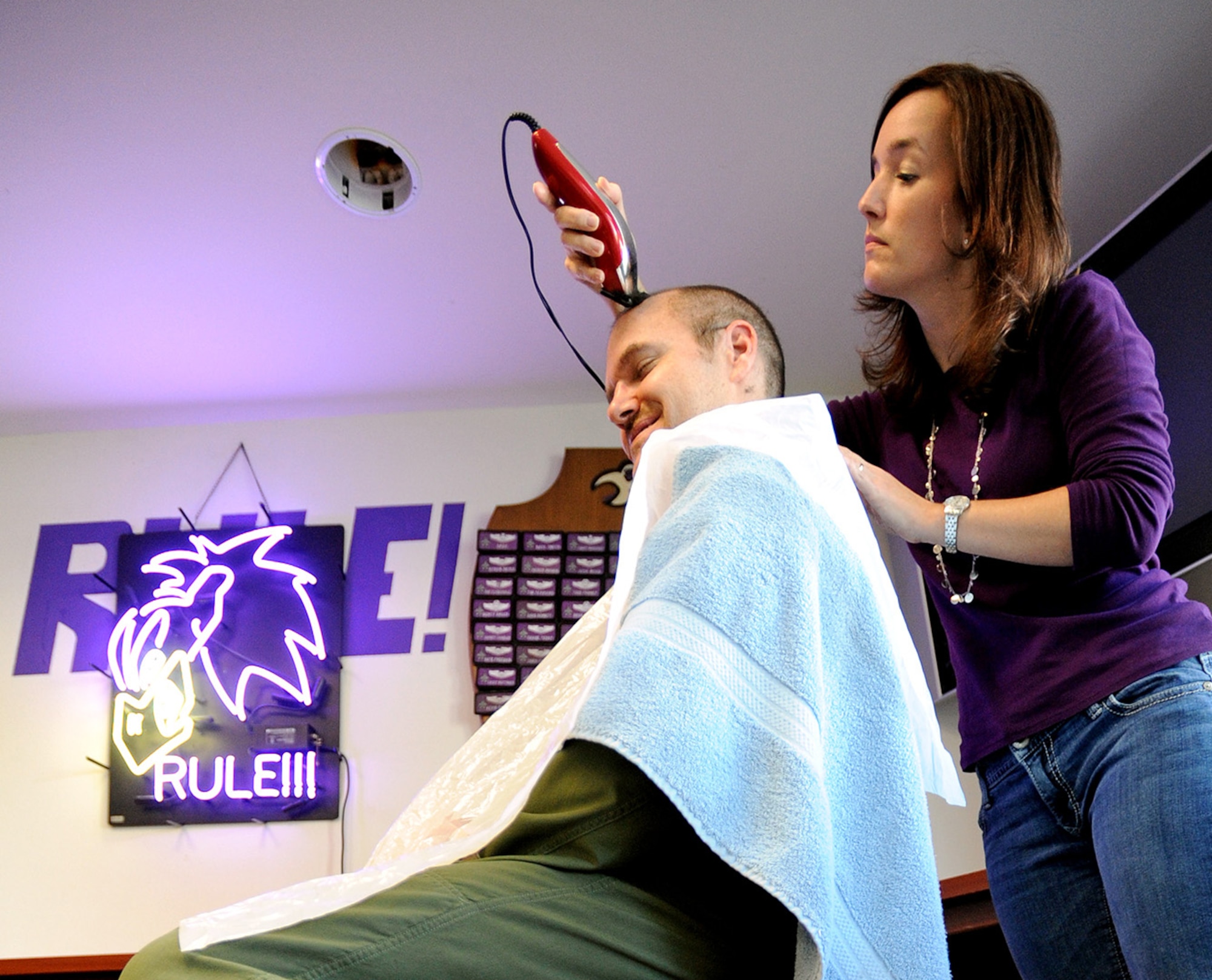 Jeri Helton, wife of Maj. Lee Helton, a 510th Fighter Squadron pilot, shaves the head of Lt. Col. Andrew Griffin, 510th Fighter Squadron director of operations, March 28, 2014, at Aviano Air Base, Italy. Helton and fellow spouse, Brittany Velasquez, wife of Capt. Alfred Velasquez Jr., 510th Fighter Squadron plans and programs chief, shaved a dozen fighter pilots’ heads to honor Brayden Mitchell, the son of late F-16 fighter pilot, 2nd Lt. Dave Mitchell. Brayden, 5, is currently battling kidney cancer. (U.S. Air Force photo/Staff Sgt. R.J. Biermann)