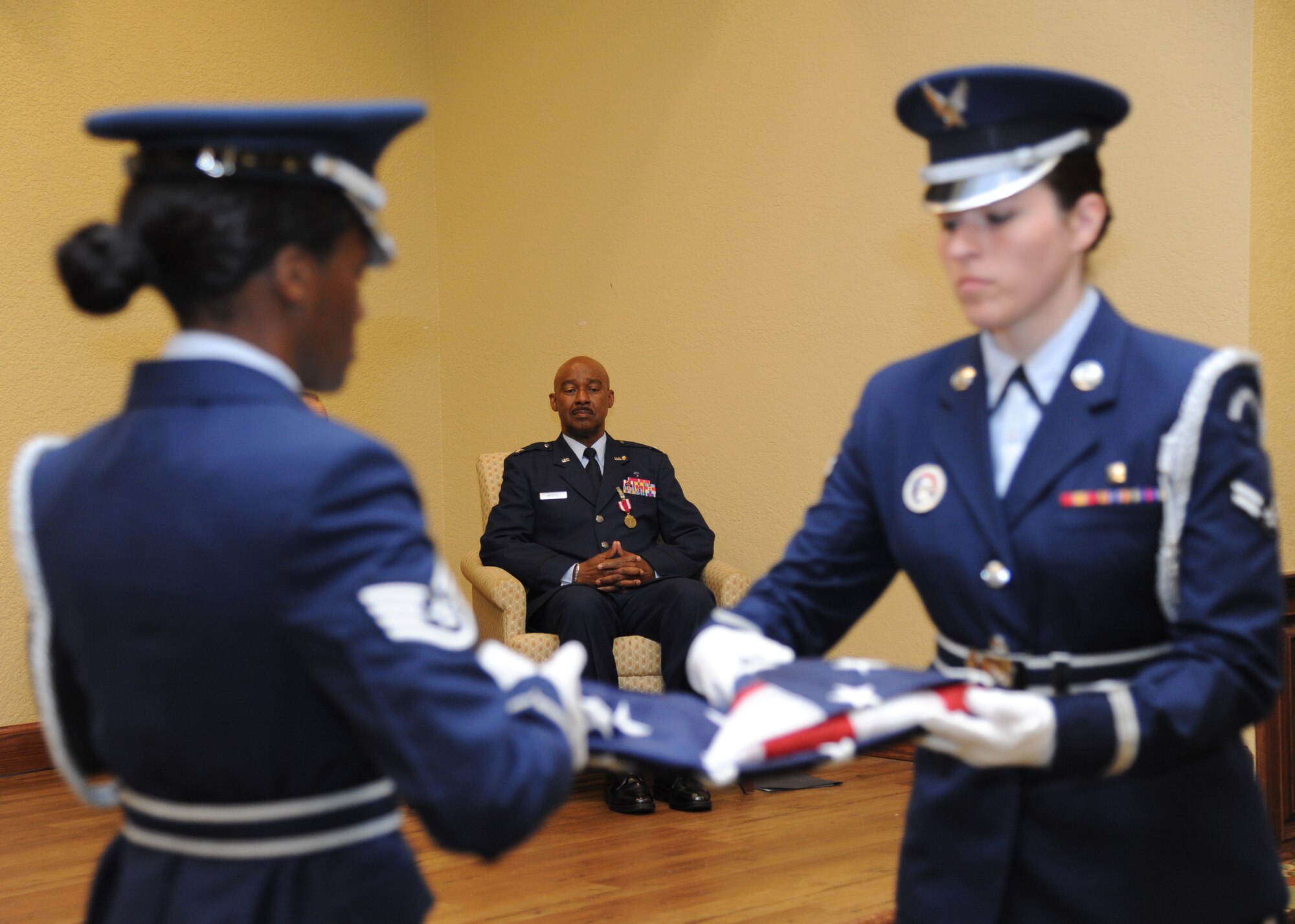 Chaplain (Col.) Wilfred Bristol, 81st Training Wing, watches as Keesler honor Guard members, Staff Sgt. LaShauna Brown and Airman 1st Class Kayla Sloan, fold a U.S. flag during a flag folding ceremony for Bristol’s retirement ceremony  March 28, 2014, at the Bay Breeze Event Center, Keesler Air Force Base, Miss.  He retired with more 29 years of military service.  (U.S. Air Force photo by Kemberly Groue)