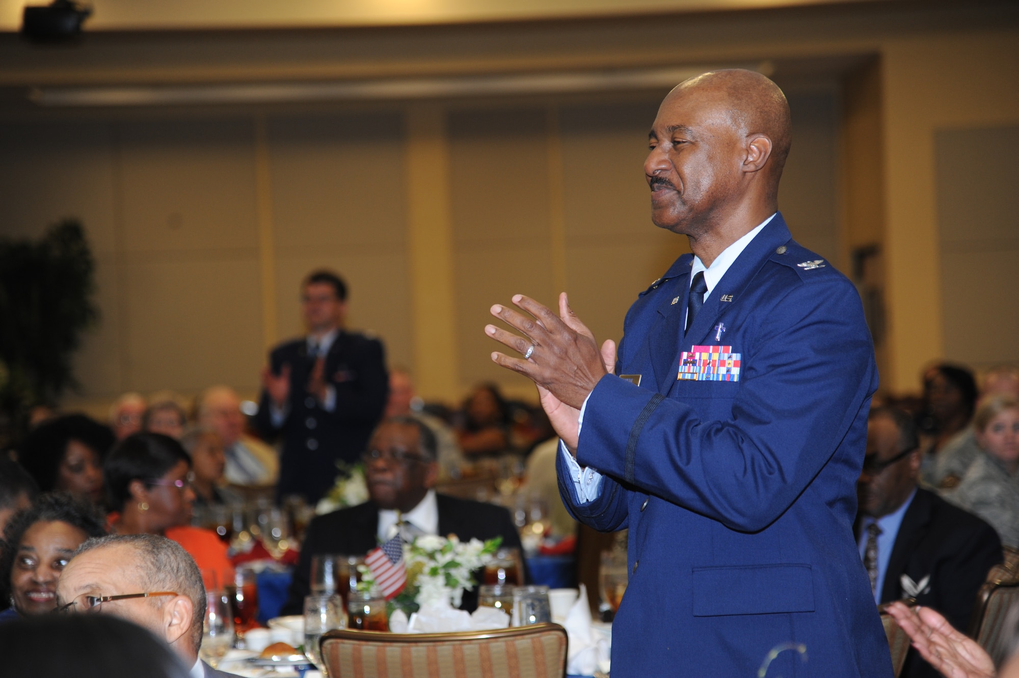 Chaplain (Col.) Wilfred Bristol, 81st Training Wing, applauds as the Keesler gospel choir performs a special selection during his retirement ceremony March 28, 2014, at the Bay Breeze Event Center, Keesler Air Force Base, Miss.  He retired with more than 29 years of military service.  (U.S. Air Force photo by Kemberly Groue)