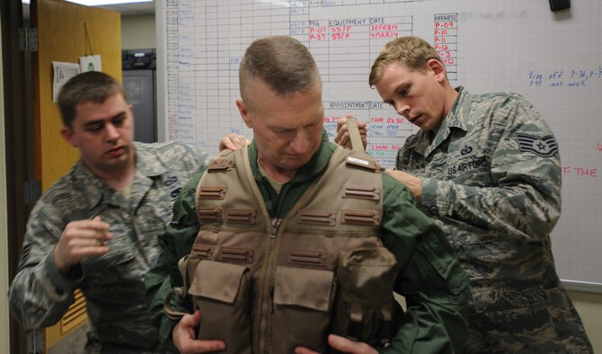Staff Sgt. Daniel Danker, 8th Operations Support Squadron aircrew flight equipment specialist, left, and Staff Sgt. Jeffrey Morris, 8th OSS AFE specialist, fit U.S. Army Command Sgt. Maj. John Troxell’s, United States Forces Korea command sergeant major, survival vest for his familiarization flight at Kunsan Air Base, Republic of Korea, Mar. 27, 2014. Troxell visited with Kunsan’s Airmen and saw how the Wolf Pack stays prepared and ready to fight tonight both on the ground and in the air. (U.S. Air Force photo by Senior Airman Armando A. Schwier-Morales/Released)