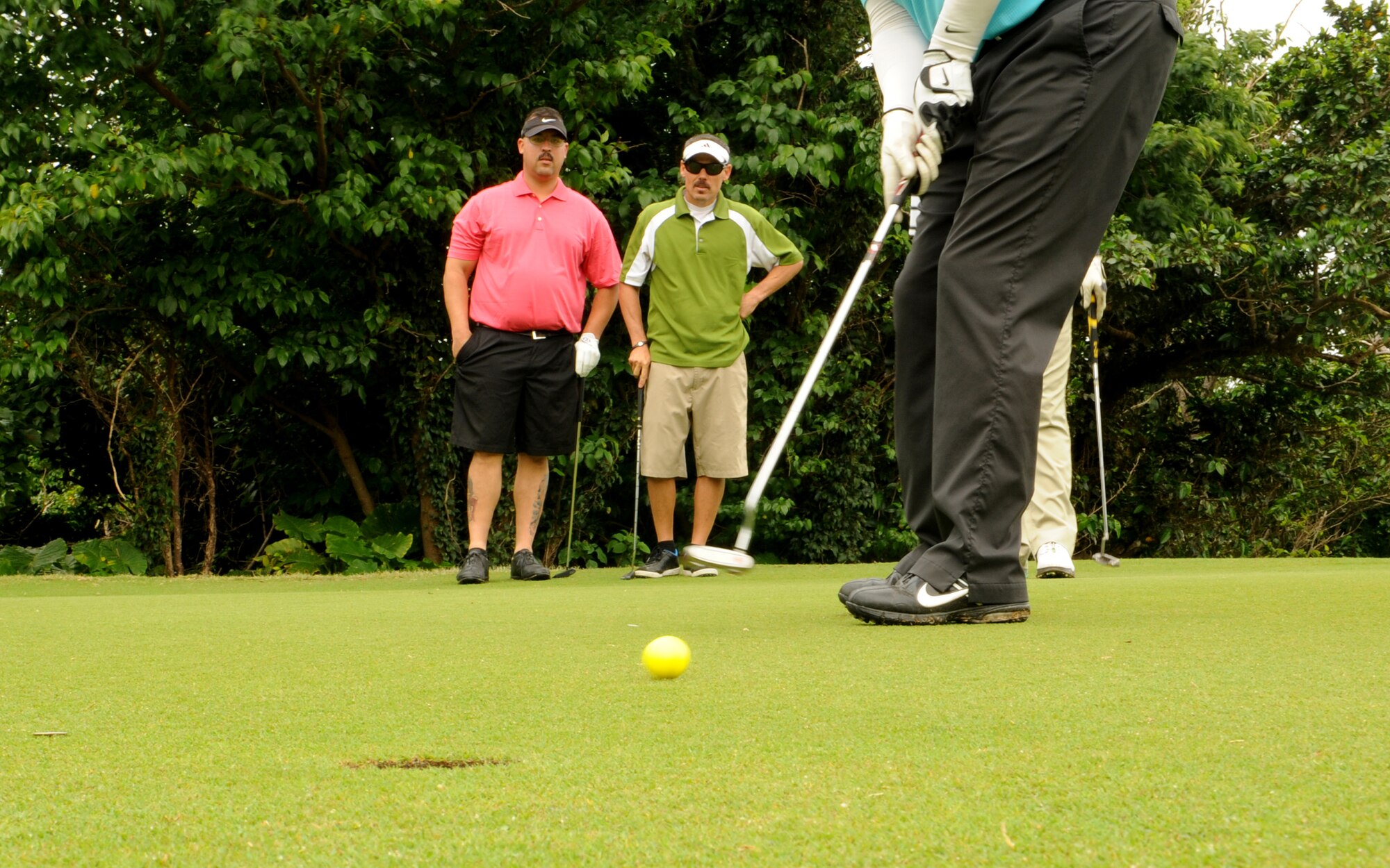Pete Lettkeman, 18th Maintenance Group unit program coordinator, takes a short putt while his friends Shane Anderson, center, and Tech. Sgt. Kevin Kiner, left, watch behind him during the 2014 Sexual Assault Program and Response Golf Tournament on Kadena Air Base, Japan, March 28, 2014. Kadena's SAPR team sponsored the event to raise awareness for sexual assault prevention and it's one of many events they have organized for Sexual Assault Awareness Month this year.  Kiner is a 961st Aircraft Maintenance Unit instrument and flight control systems lead technician and Anderson works for 18th Maintenance Group Air Force engineering technical services. (U.S. Air Force photo by Airman 1st Class Zackary Henry)