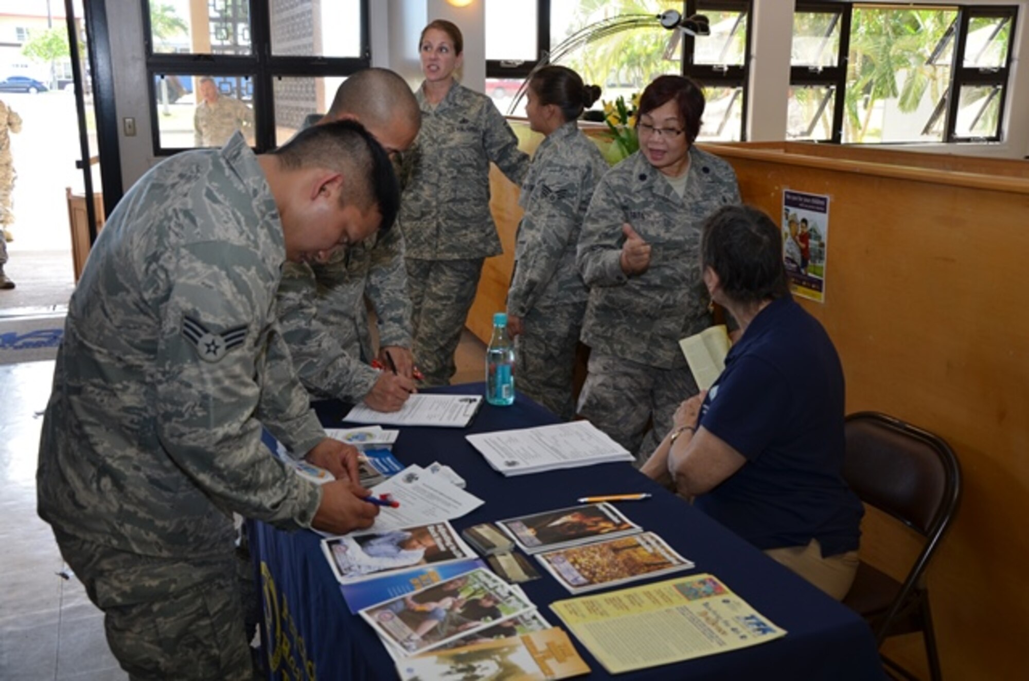 Members of the 624th Regional Support Group gather around a table set up by Karen Orcutt, right in civilian clothes, case facilitator for the Air Force Reserve Command's Psychological Health Advocacy Program (PHAP), to fill out contact sheets to indicate they are interested in being contacted by PHAP about specific resources available to them and their families, Joint Base Pearl Harbor-Hickam, Hawaii, Mar. 9, 2014. The PHAP briefing was held during the 624th RSG's commander's call in order to inform all unit members, regardless of deployment status, of these free mental health resources. (U.S. Air Force photo by Tech. Sgt. Phyllis Keith)
