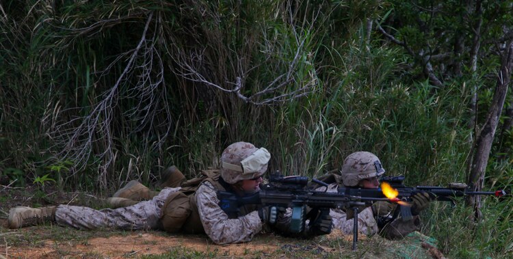 Lance Cpl. Elias J. Burne, front, and Lance Cpl. Cody Gammons provide covering fire March 19 during response to ambush training as part of a field training exercise in the Central Training Area, Okinawa. After taking simulated enemy fire, the Marines returned suppressive fire, which allowed other Marines to flank the attackers. Burne and Gammons are law enforcement specialists with Company A, 3rd Law Enforcement Battalion, III Marine Expeditionary Force Headquarters Group, III MEF.