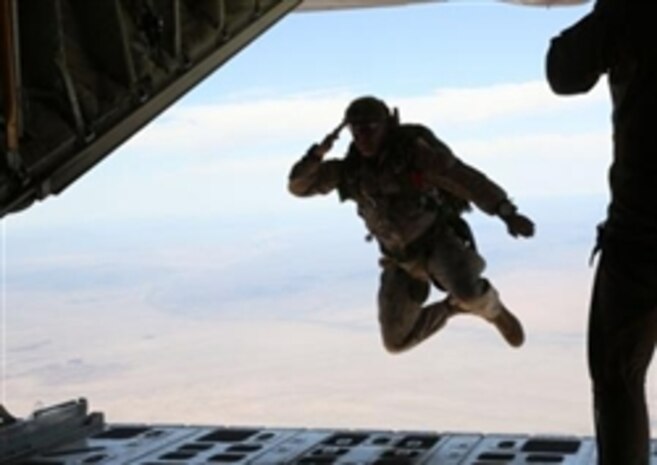 Marine Corps Master Sgt. Randy Messineo, operation chief, Company B, 1st Reconnaissance Battalion, and a native of Boston, salutes the crew of a C-130 Hercules aircraft as he jumps out of it during a double-bag static line course held in Parker, Ariz., March 24, 2014. A static line is a cord attached from one end of the aircraft to the other. When the Marine jumps from the plane, the line pulls the deployment bag out of the pack on the Marine’s back causing the parachute to inflate.
