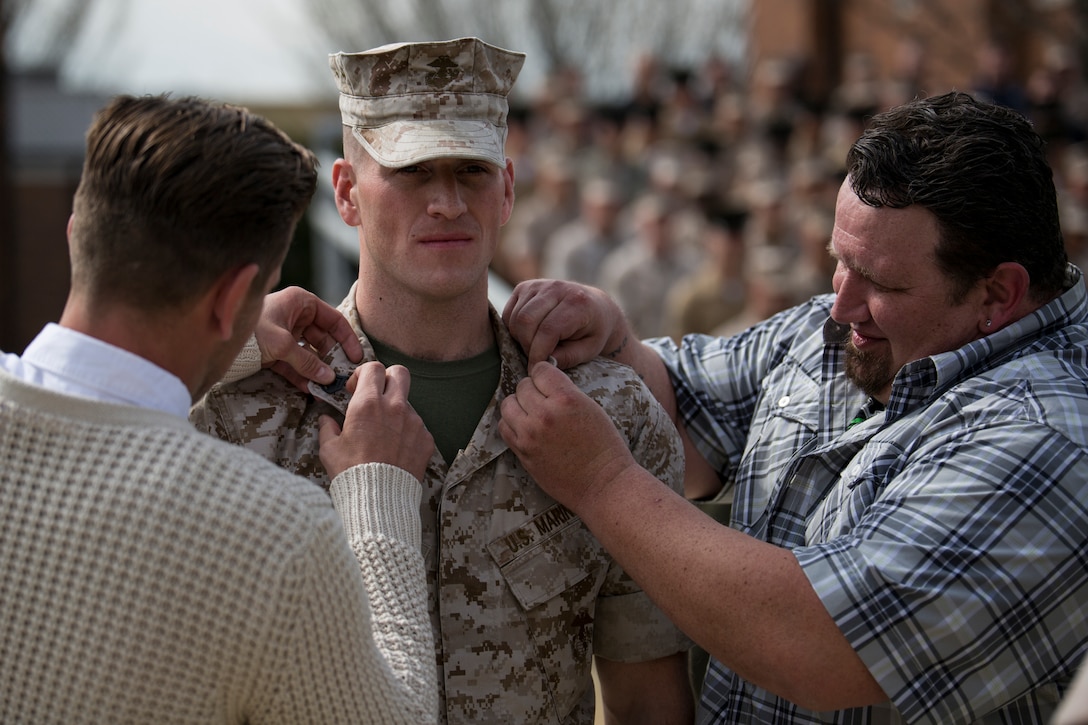 Staff Sgt. Sean Yates, a 27-year-old Puyallup, Wash. native and former member of the Marine Corps Color Guard, gets staff sergeant chevrons pinned on his color by his brothers during a meritorious promotion ceremony at Marine Barracks Washington, D.C., April 2. Yates previously served as the guide for the Color Guard and was the honor graduate of Corporals Course, Martial Arts Instructor Course, Foreign Weapons Instructor Course, and Sergeants Course. (Official Marine Corps photo by Cpl. Larry Babilya/Released)