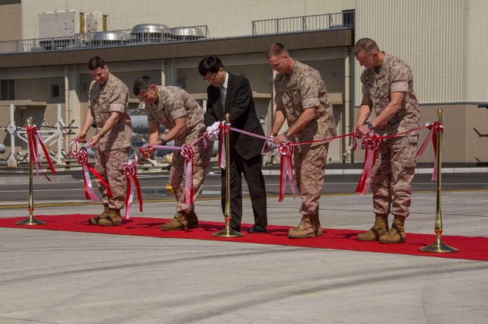 From left to right, Col. Robert V. Boucher, commanding officer of Marine Corps Air Station Iwakuni, Japan, Maj. Gen. Juan G. Ayala, commander of Marine Corps Installations Command, Takafumi Fujii, director general of the Chugoku-Shikoku Defense Bureau, Brig. Gen. Steven Rudder, commanding general of 1st Marine Aircraft Wing, and Col. Hunter H. Hobson, commanding officer of Marine Aircraft Group 12, cut a ceremonial ribbon signifying the official opening of new facilities during the MAG-12 and Marine Aviation Logistics Squadron 12 ribbon cutting ceremony aboard station March 27, 2014. The Defense Policy Review Initiative built the new facilities as part of the ongoing construction focused on rebuilding 77 percent of the station.