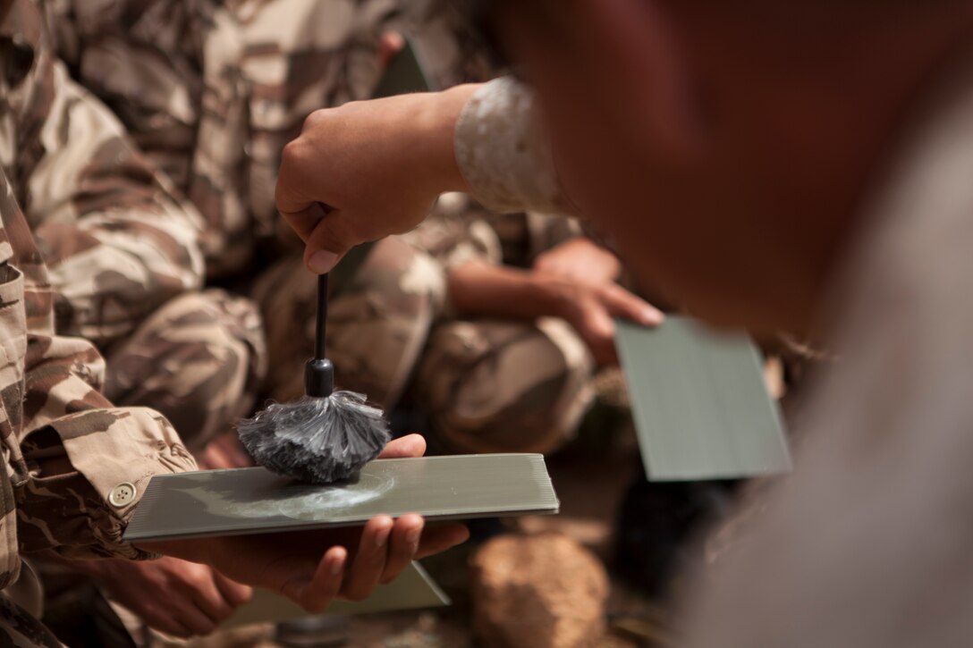 U.S. Marine Corps Sgt. Matthew D. Hanson, military policeman, 2nd Law Enforcement Battalion, 2nd Marine Expeditionary Brigade, II Marine Expeditionary Force shows a member of the Royal Moroccan Armed Forces (FAR) how to bust for finger prints during a tactical site exploitation class as part of exercise African Lion 2014 on Tifnit FAR Base in Agadir, Morocco, Mar. 29, 2014. African Lion is conducted as a combined joint exercise between the Kingdom of Morocco and the U.S. Forces to strengthen relationships and military operability in the region. (U.S. Marine Corps Photo by Cpl. Alexandria Blanche, 2D MARDIV COMCAM/Released)