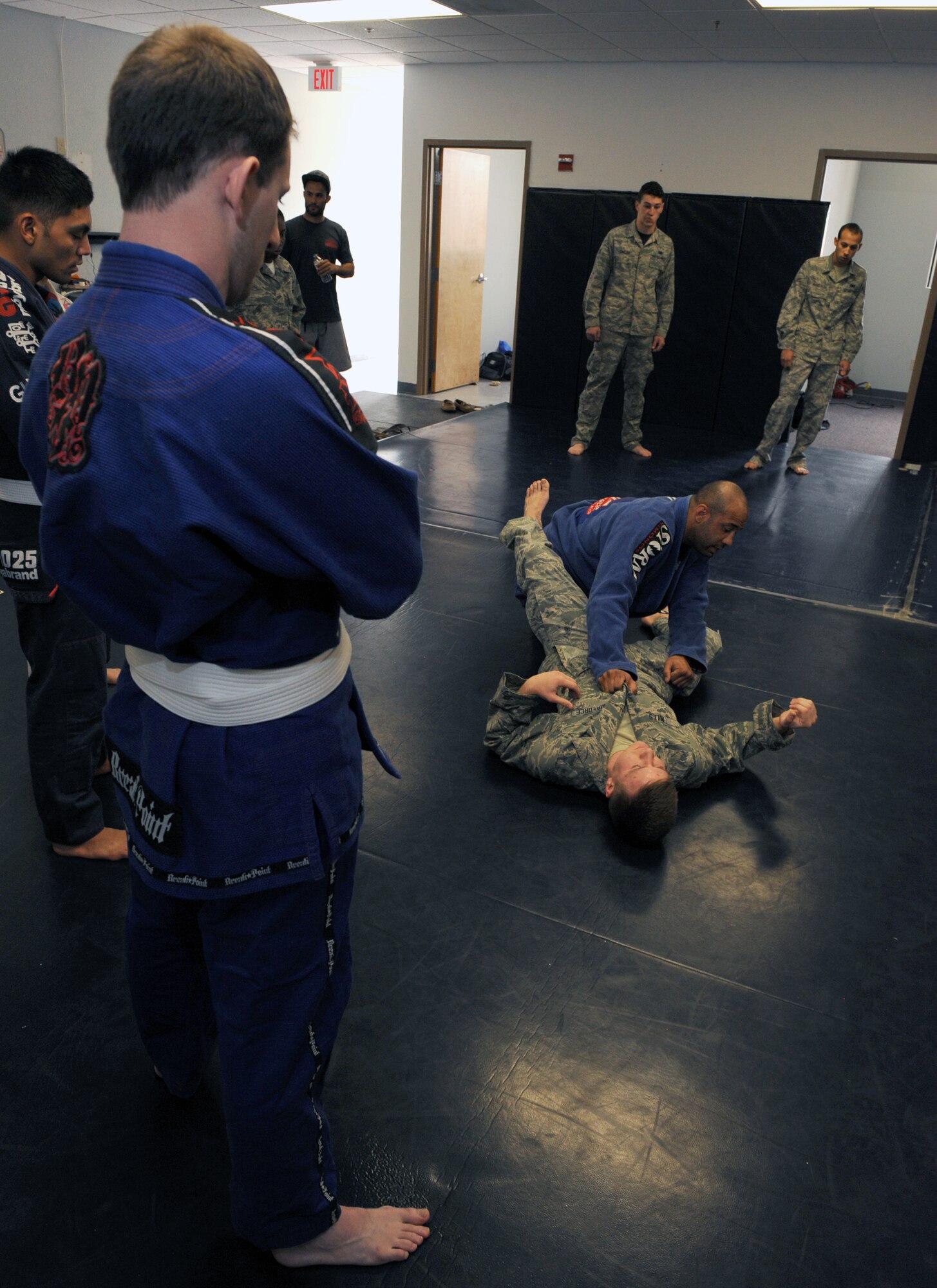U.S. Air Force Staff Sgt. Adrian Allred, 355th Maintenance Group aircraft maintenance scheduler, looks on as Senior Airman Garrett Clark, combatives instructor and 355th Aircraft Maintenance Squadron engine aircraft mechanic, demonstrates a combatives situation during a seminar at Davis-Monthan Air Force Base, Ariz., March 30, 2014. The goal of the seminar was to spread interest in combatives so more Airmen can gain experience in hand-to-hand combat. (U.S. Air Force photo by Airman 1st Class Chris Drzazgowski/Released)